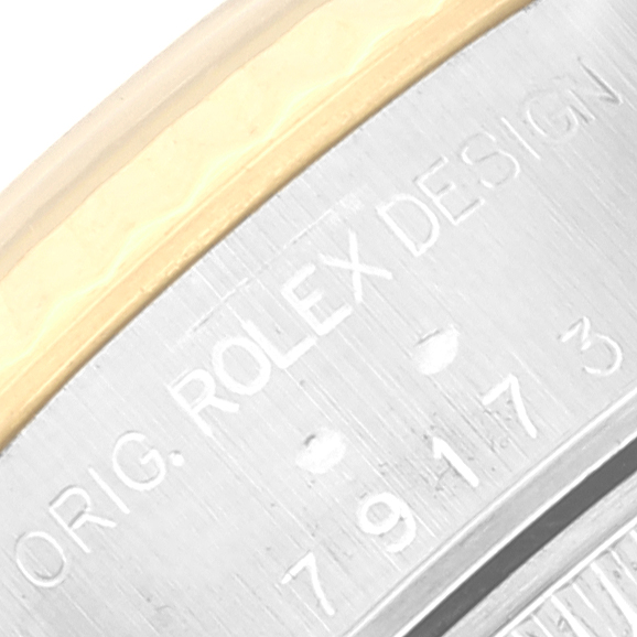 This image shows a close-up of the Rolex Datejust 79173 Women's Steel and Gold (two tone) Silver Dial 79173 Women's Steel and Gold (two tone) Silver Dial watch's side case with engraved text and the bezel.