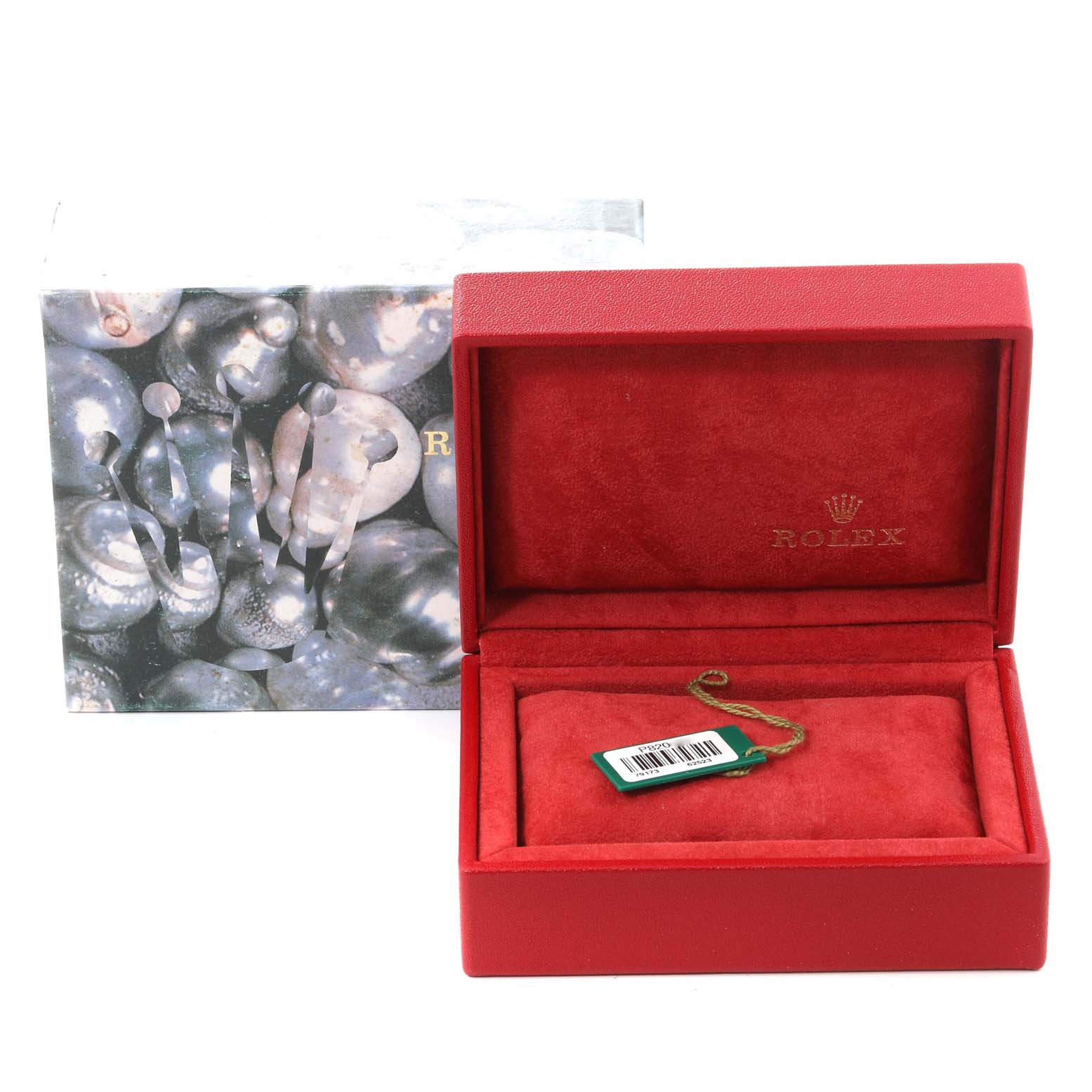 The image shows a red Rolex box designed for the Datejust model, containing a green tag with a barcode, and the outer packaging in the background.