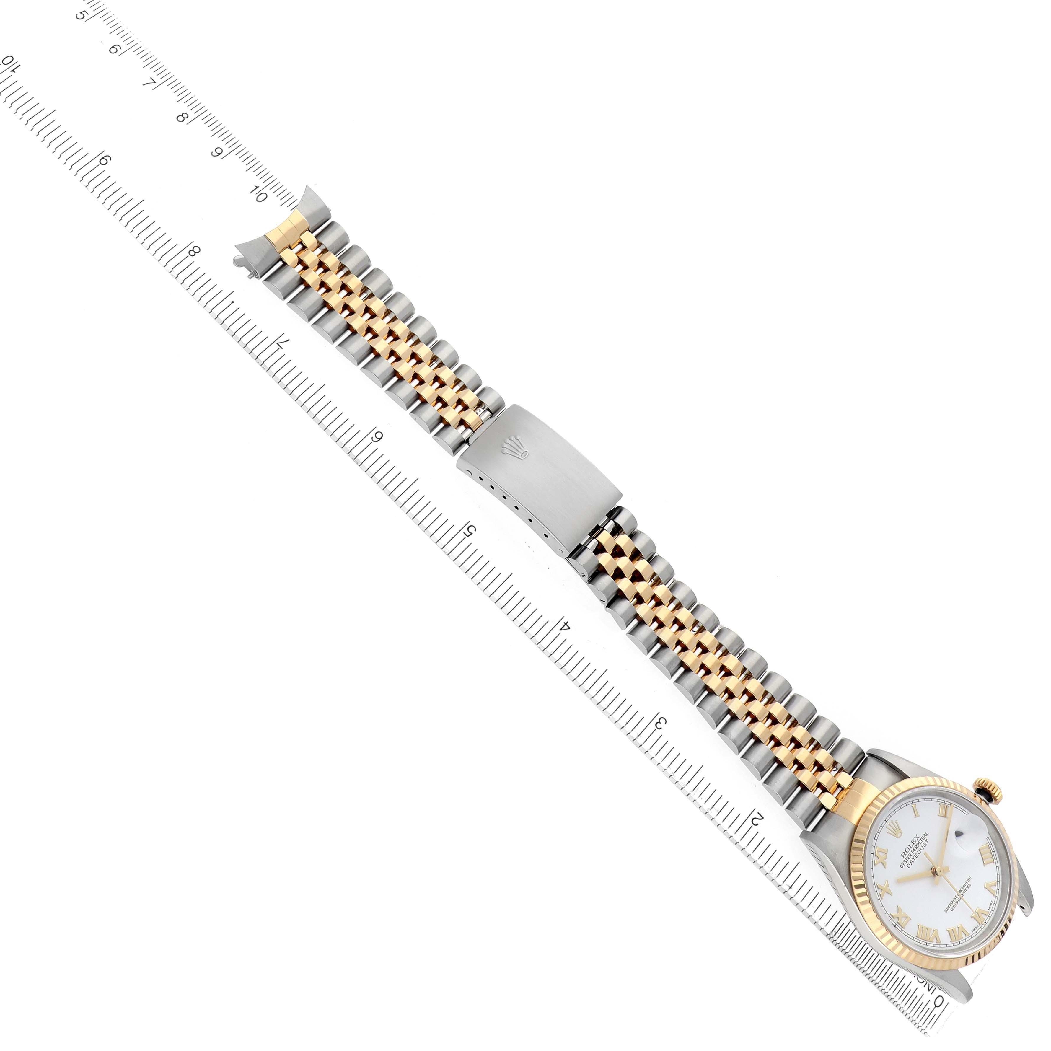 The Rolex Datejust 16233 Men's Steel and Gold (two tone) White Dial watch is displayed from an overhead angle, showing the bracelet, clasp, and watch face alongside a ruler.