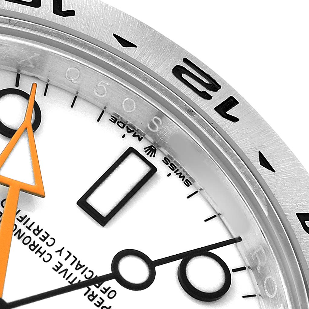 The image shows a close-up of the Rolex Explorer 226570 Men
s Stainless Steel White Dial
s bezel and dial, highlighting the hour markers and orange hand.
