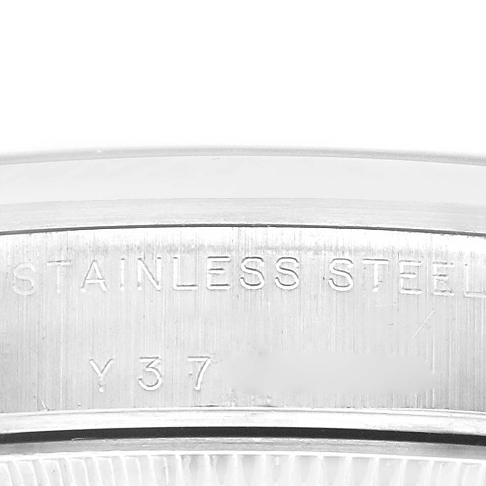 The image shows a close-up of the case side of a Rolex Oyster Perpetual 77080 Women's Stainless Steel Black Dial, highlighting "Stainless Steel" engraving.