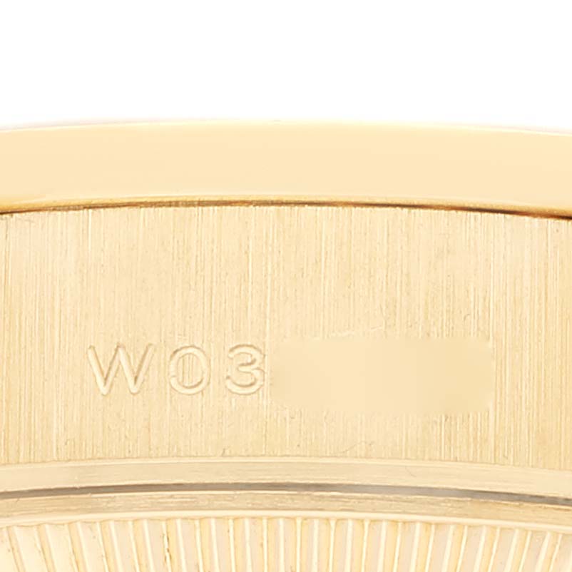 This close-up image shows the engraved serial number on the side case of a Rolex President 69138 Women's Yellow Gold Black Dial 69138 Women's Yellow Gold Black Dial model watch.
