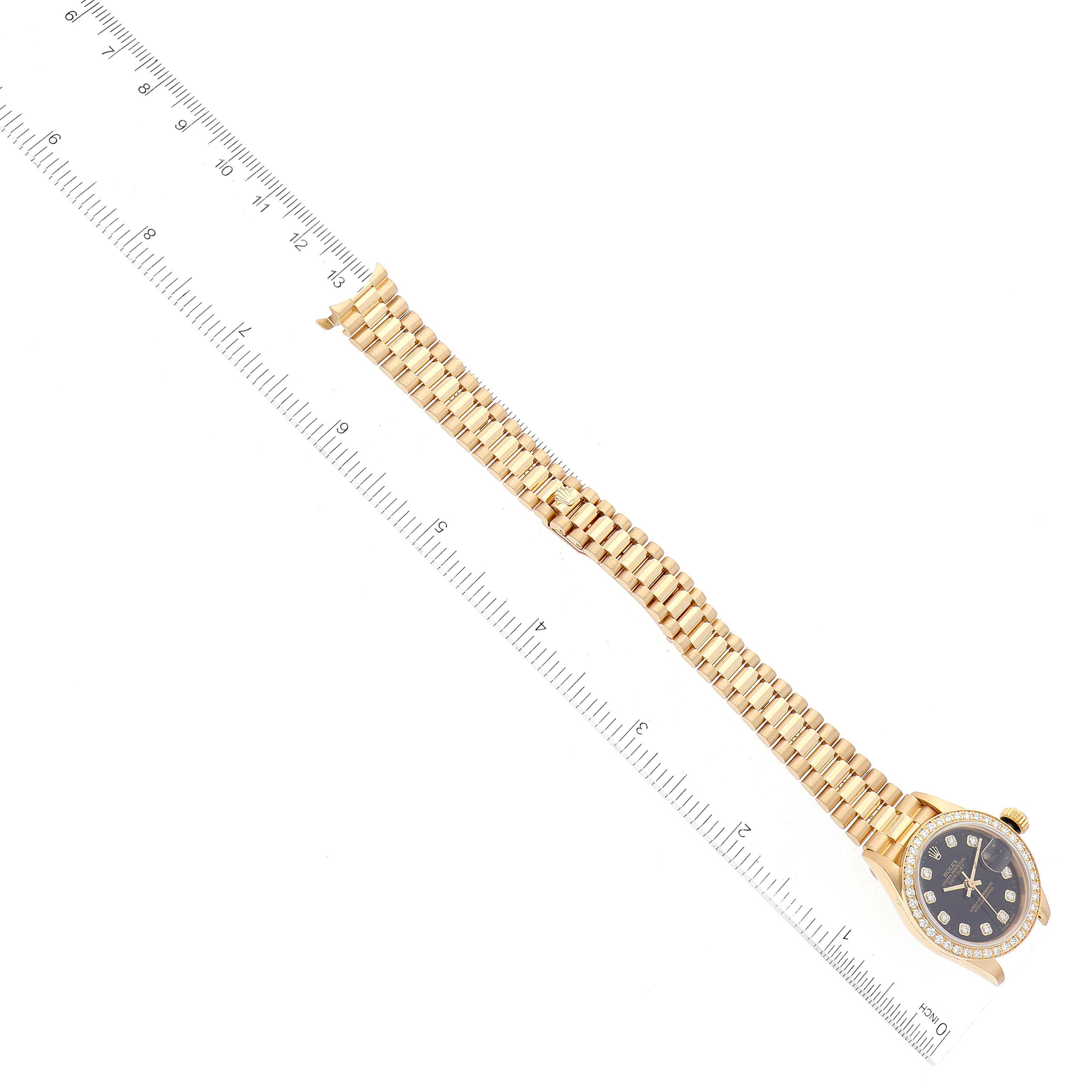 The image shows a Rolex President 69138 Women's Yellow Gold Black Dial 69138 Women's Yellow Gold Black Dial model watch from a side angle, displaying the bracelet, face, and bezel placed next to a ruler.