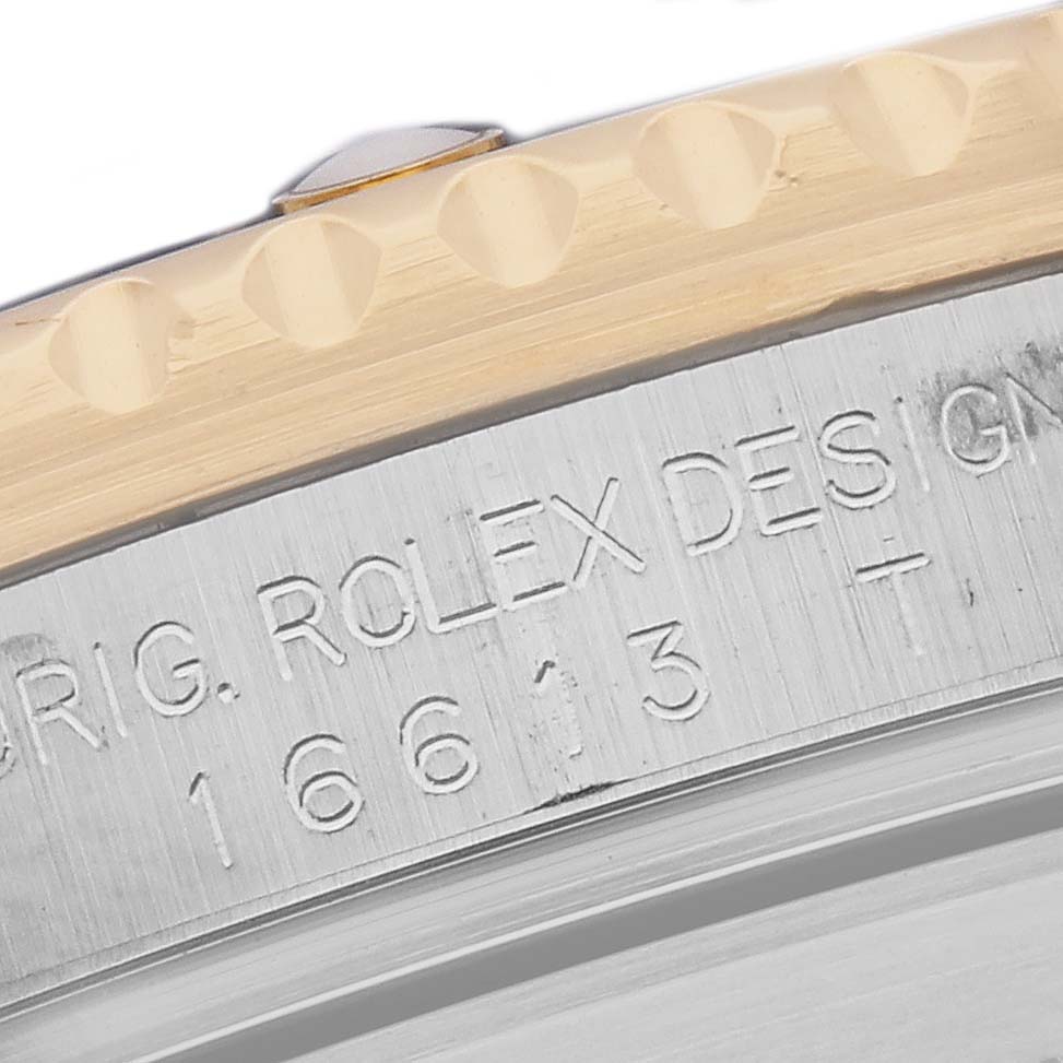 The image shows a close-up of the Rolex Submariner 16613 Men's Steel and Gold (two tone) Blue Dial's bezel and engraved side, highlighting the model number.