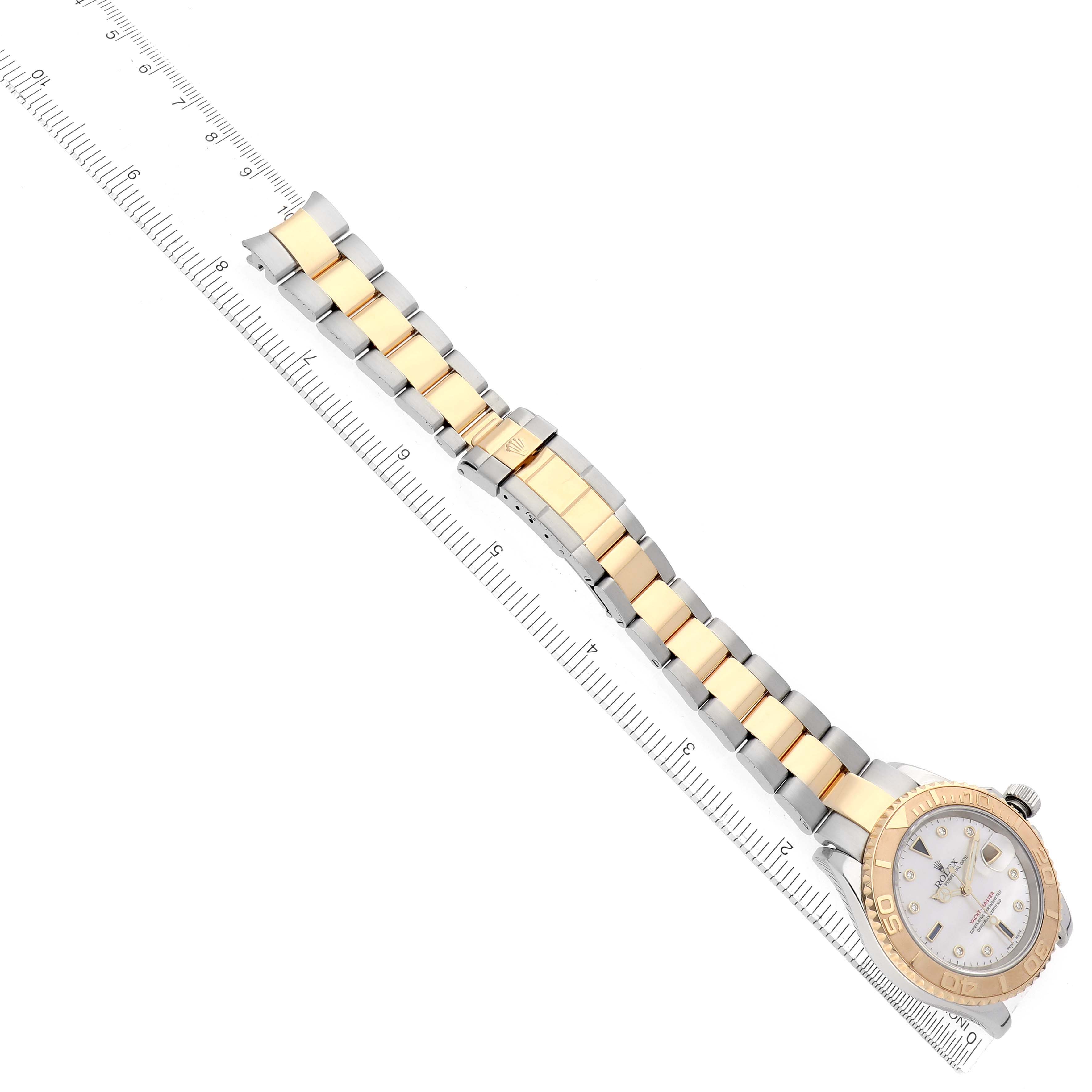 The image shows a Rolex Yacht-Master 16623 Men
s Steel and Gold (two tone) Mother of Pearl Dial watch from an overhead angle, displaying the face, bezel, and full bracelet alongside a ruler.