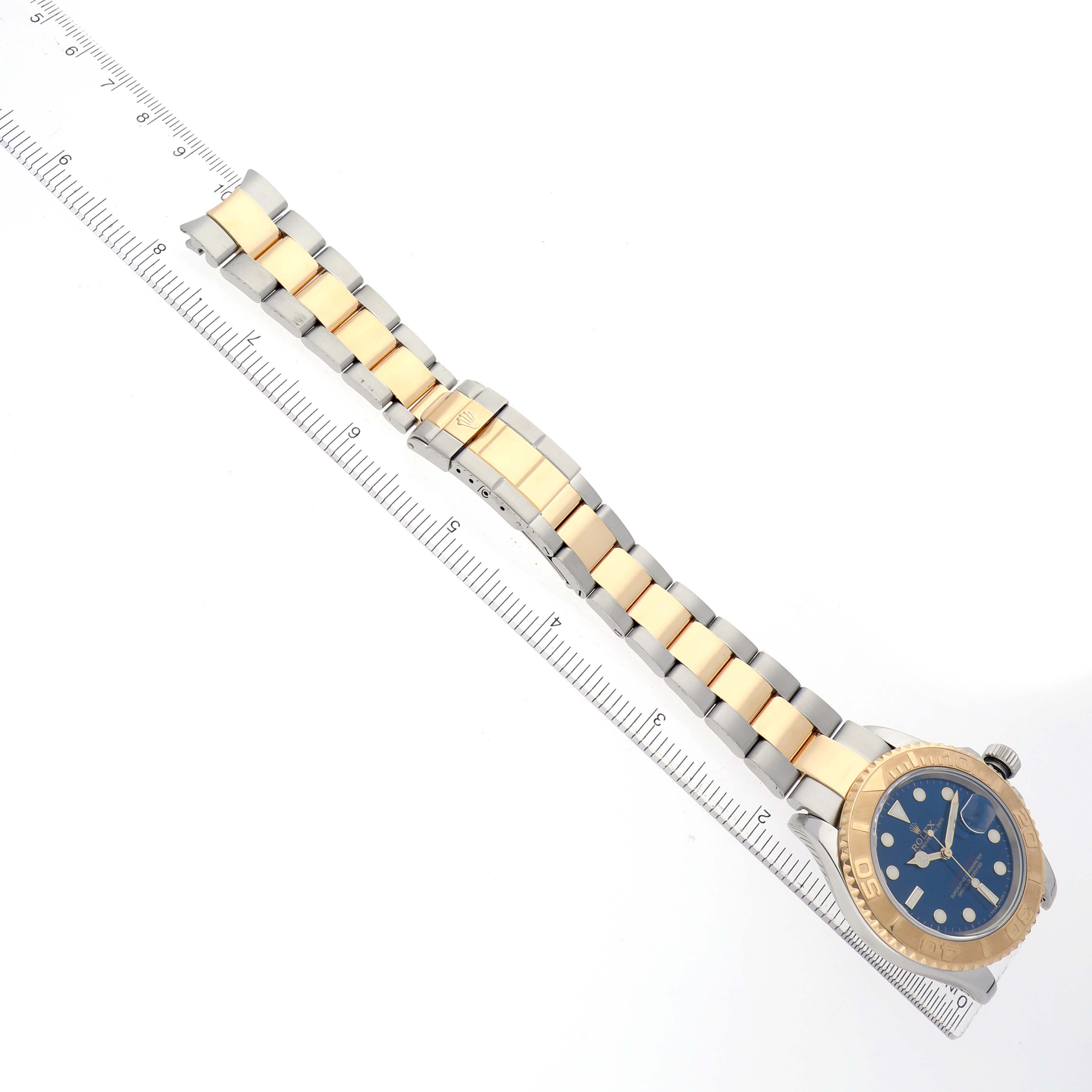 The Rolex Yacht-Master 16623 Men
s Steel and Gold (two tone) Blue Dial watch is shown from a top-down angle, displaying the bracelet, bezel, and dial alongside a ruler for scale.