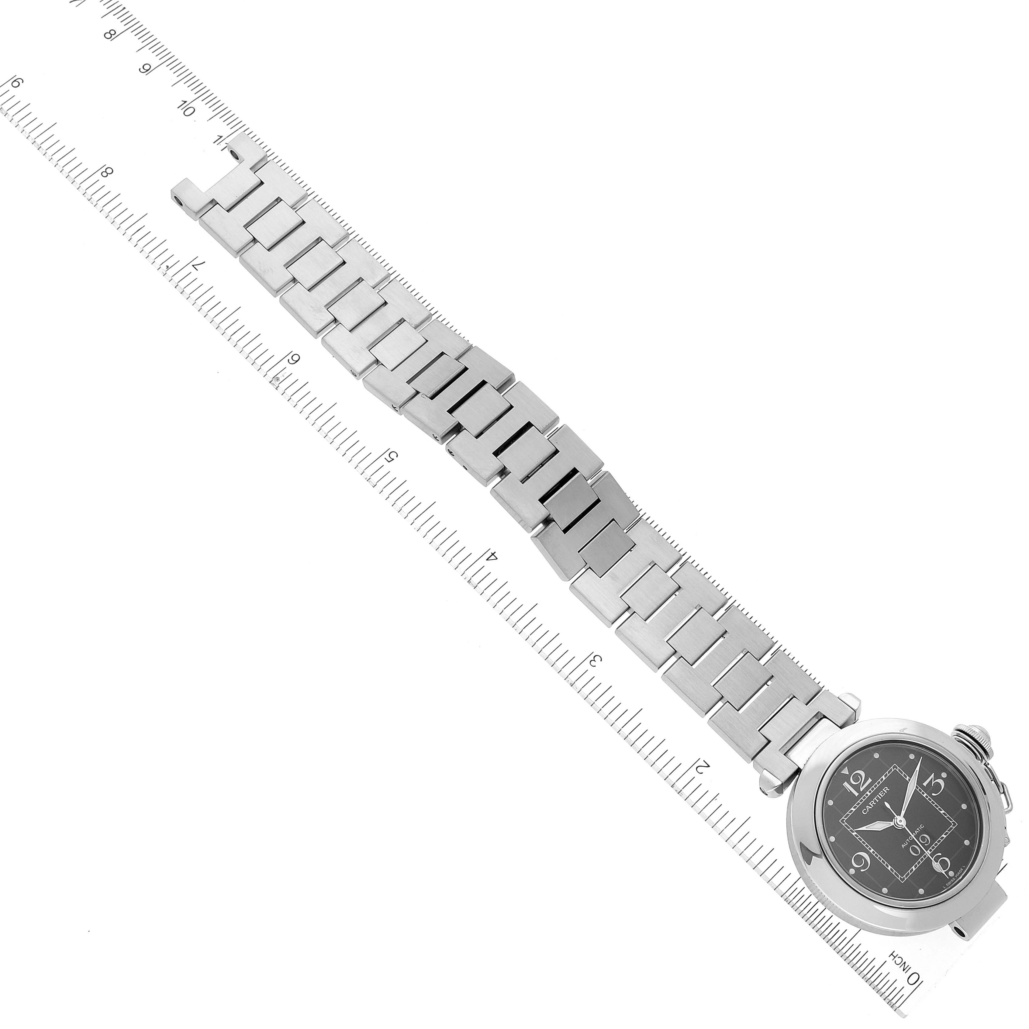 The image shows a top view of a Cartier Pasha W31053M7 Women's Stainless Steel Black Dial W31053M7 Women's Stainless Steel Black Dial watch, displaying its bracelet and face next to a ruler.