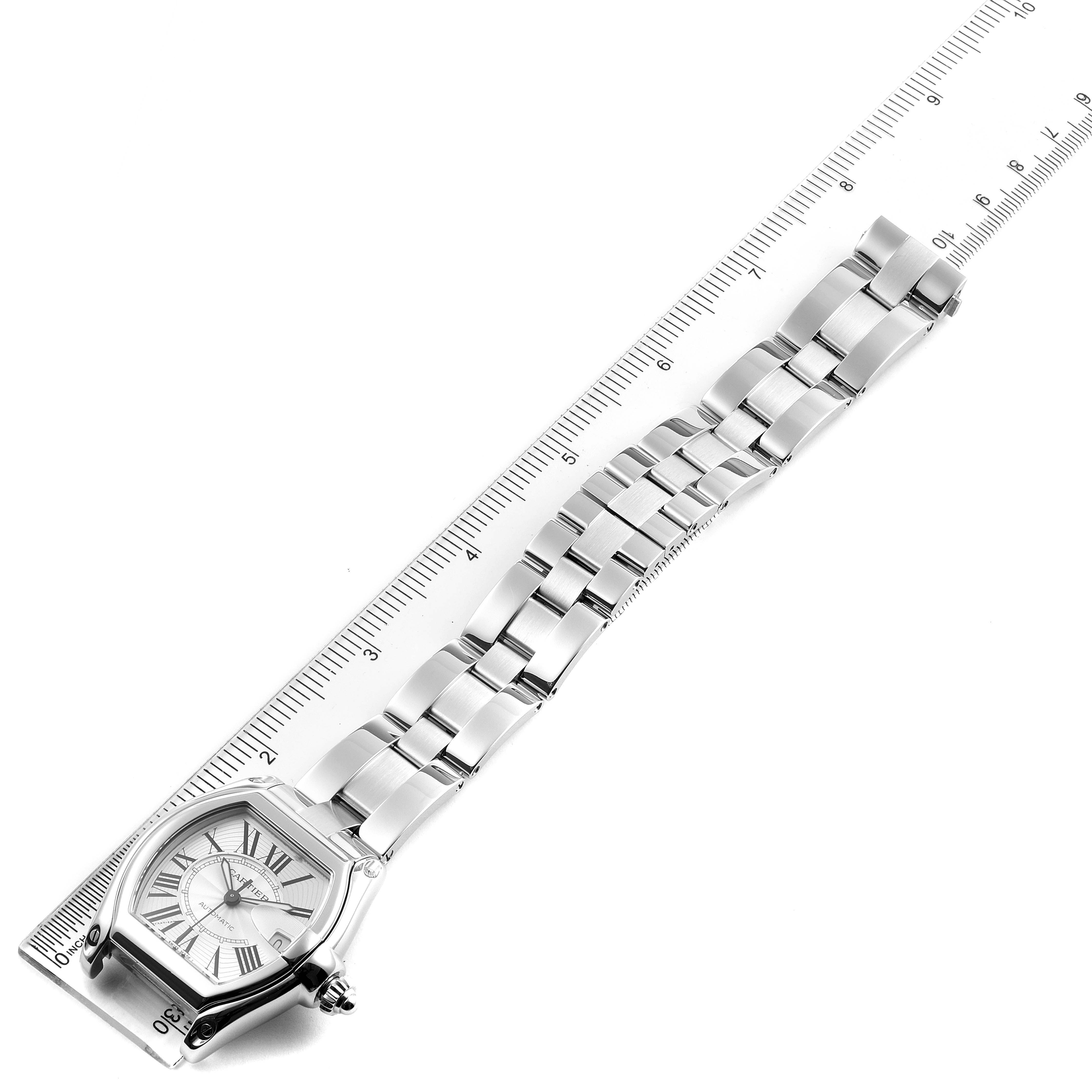 The image shows a Cartier Roadster W62025V3 Men
s Stainless Steel Silver Dial W62025V3 Men
s Stainless Steel Silver Dial watch laid flat next to a ruler, displaying its full bracelet and face from a top-down angle.