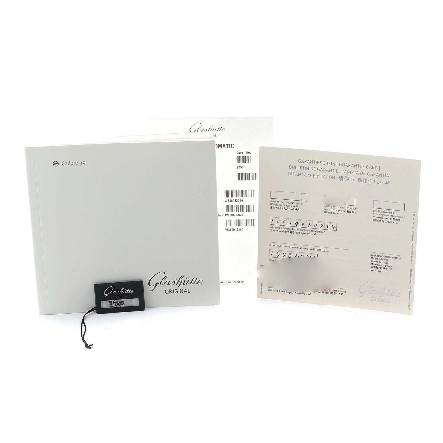 The image shows documentation and tags for the Glashütte Senator model, including a booklet, guarantee card, and hang tag.