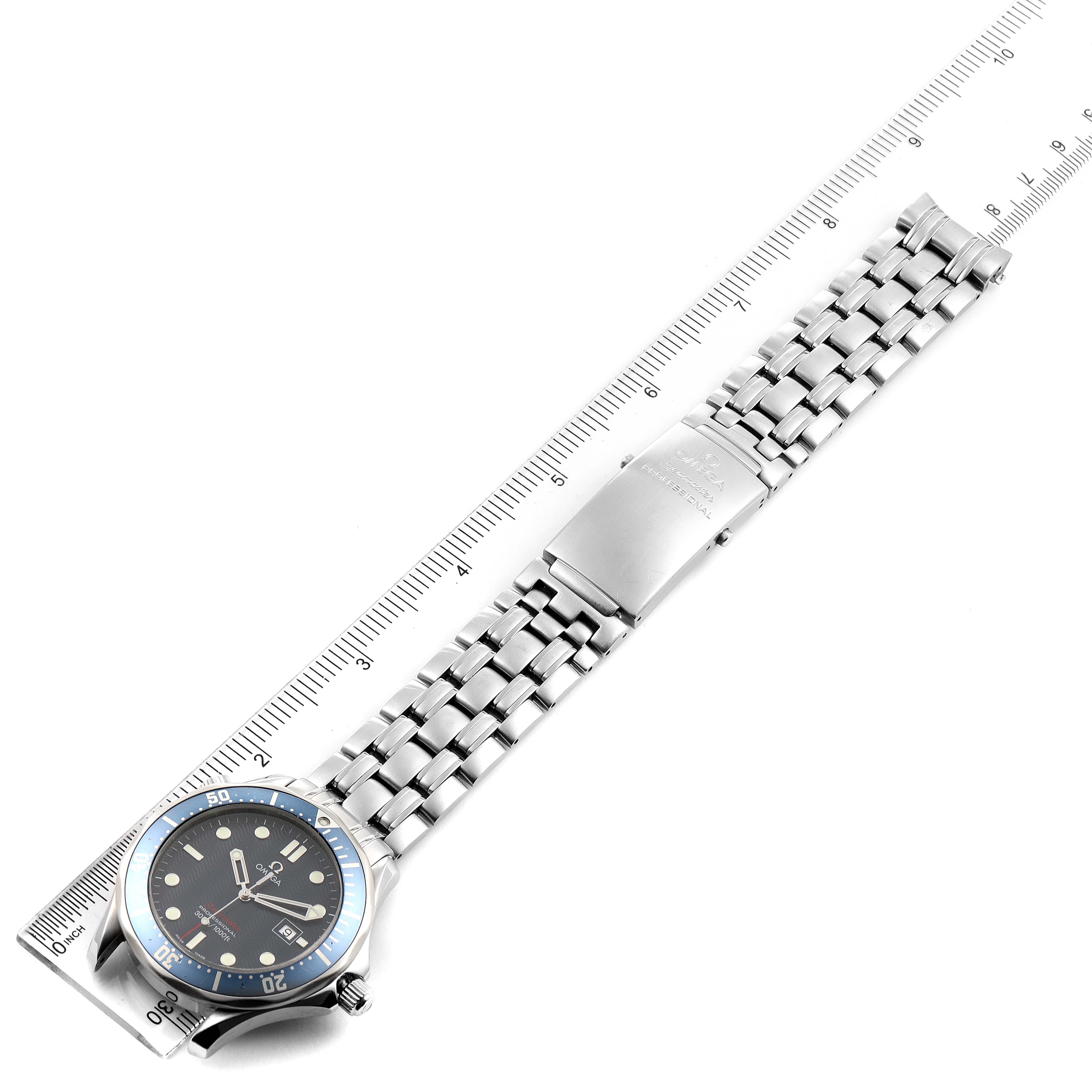 The image shows an Omega Seamaster 2221.80.00 Men
s Stainless Steel Blue Dial 2221.80.00 Men
s Stainless Steel Blue Dial watch lying flat with a metal bracelet fully extended and aligned with a ruler for measurement.