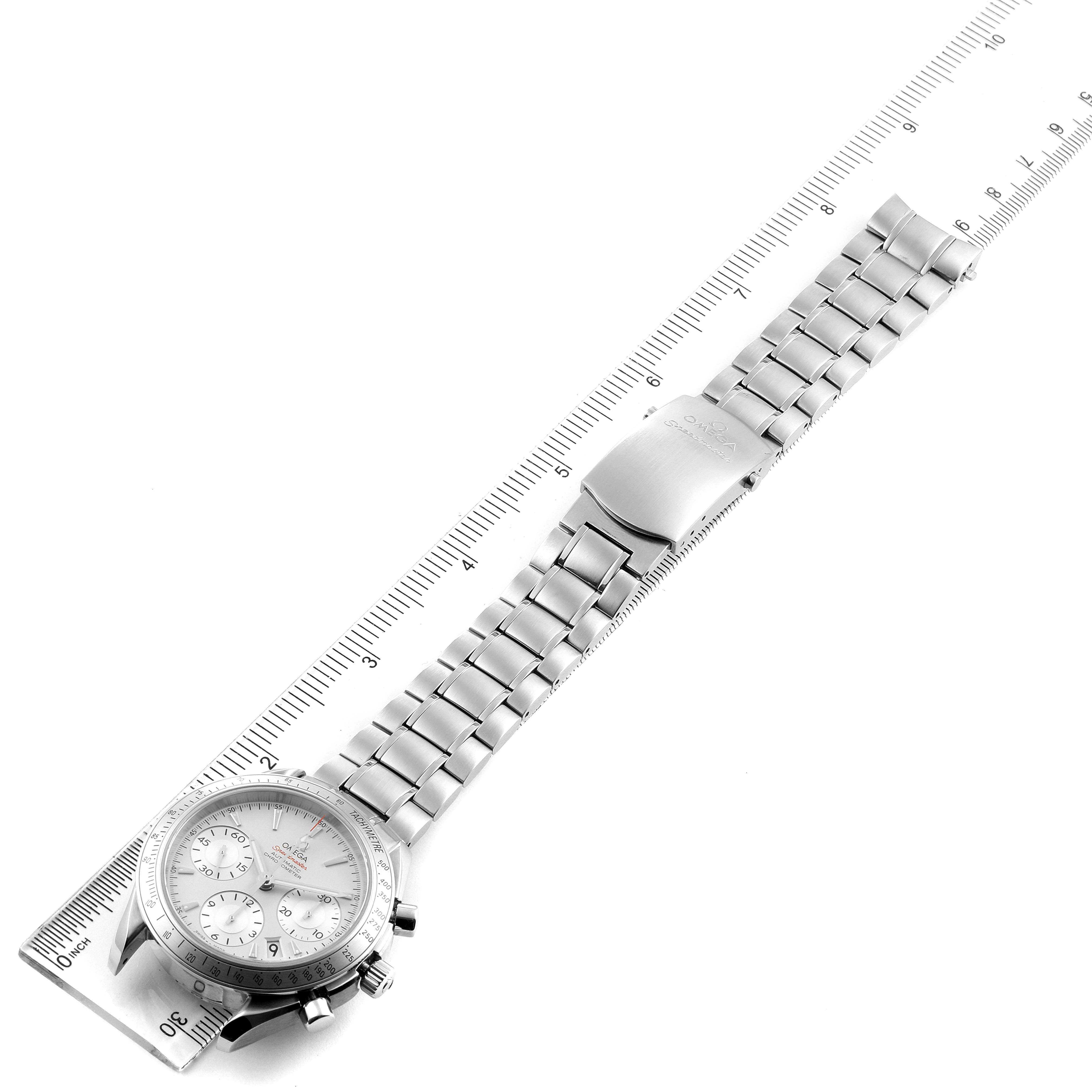 The image shows an overhead view of an Omega Speedmaster 323.10.40.40.02.001 Men
s Stainless Steel Silver Dial 323.10.40.40.02.001 Men
s Stainless Steel Silver Dial watch with its full metal bracelet laid flat next to a ruler.