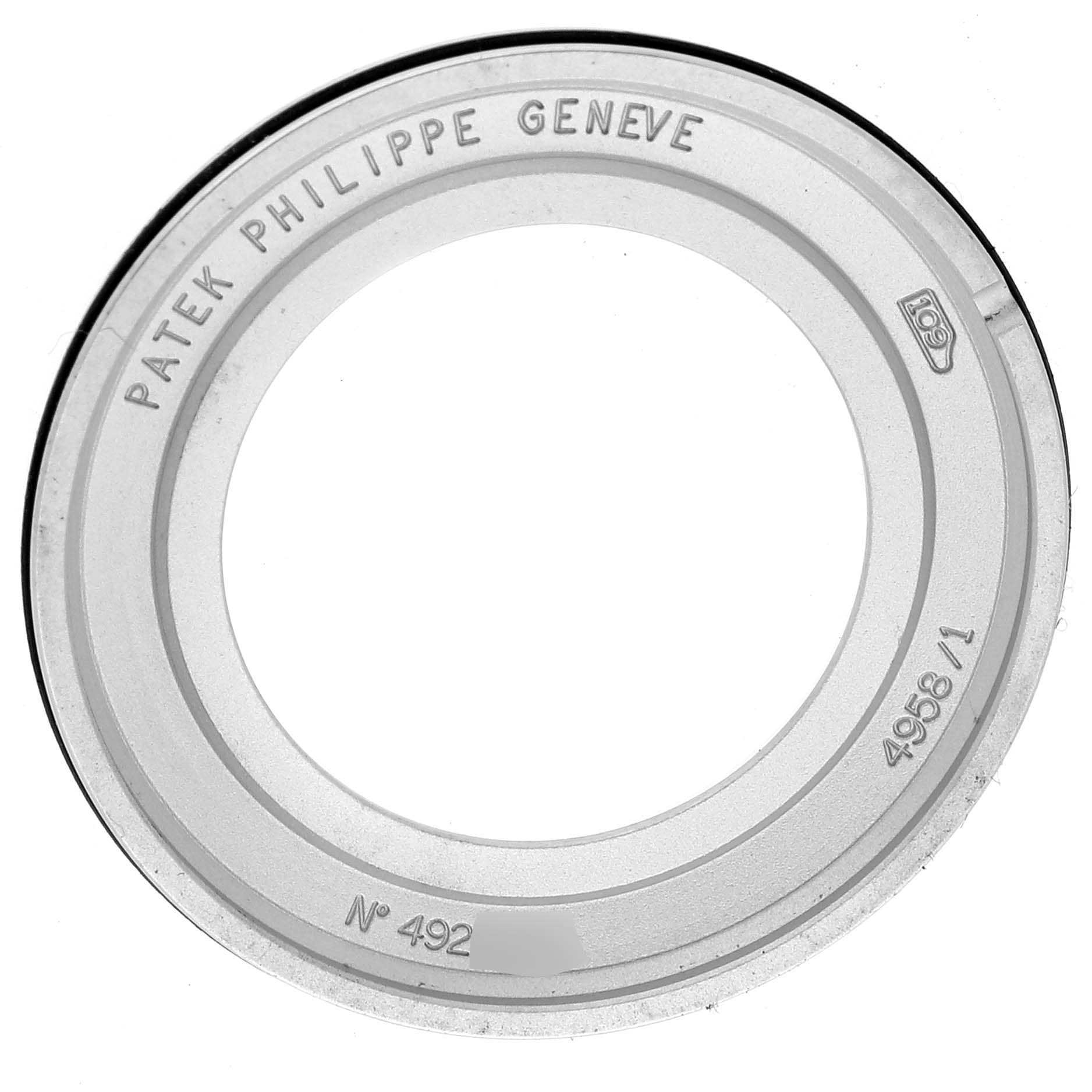 The image shows a top view of a bezel for the Patek Philippe Calatrava 4958/1G-001 Women's White Gold Silver Dial 4958/1G-001 Women's White Gold Silver Dial, displaying engraved text and serial numbers.