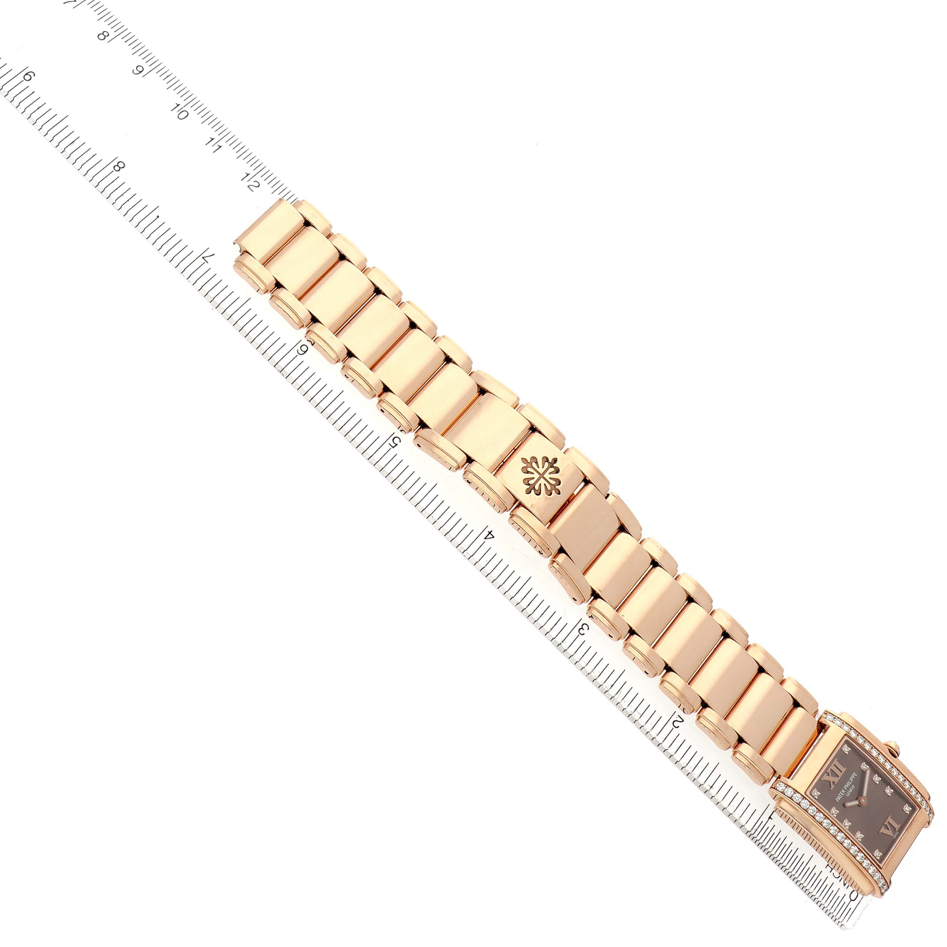 The Patek Philippe Twenty-4 4910 Women's Rose Gold Brown Dial watch is shown at an angle highlighting the bracelet and case, aligned with a ruler.