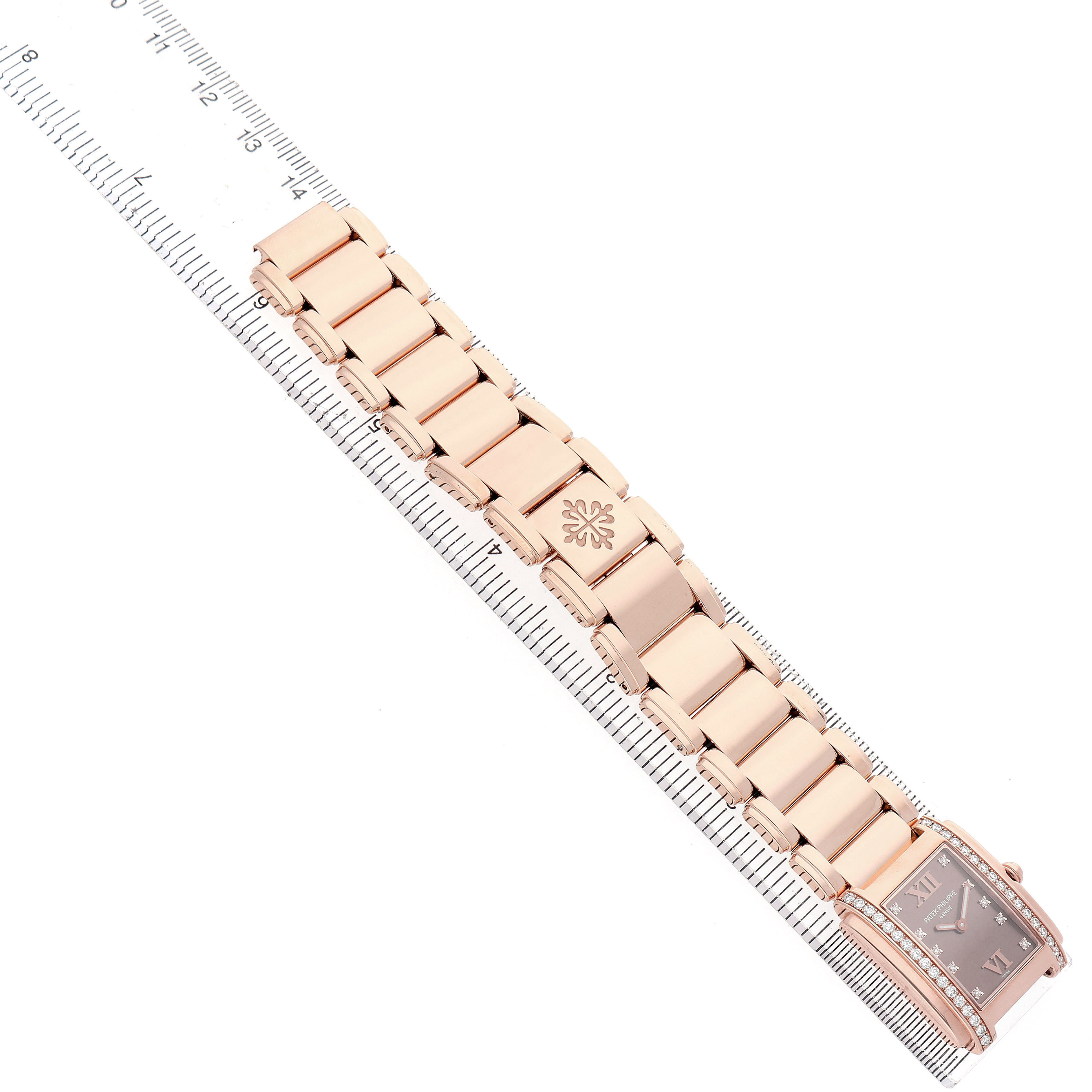 The Patek Philippe Twenty-4 4910 Women's Rose Gold Brown Dial watch is shown from a top-down angle, highlighting the bracelet and face along a ruler.