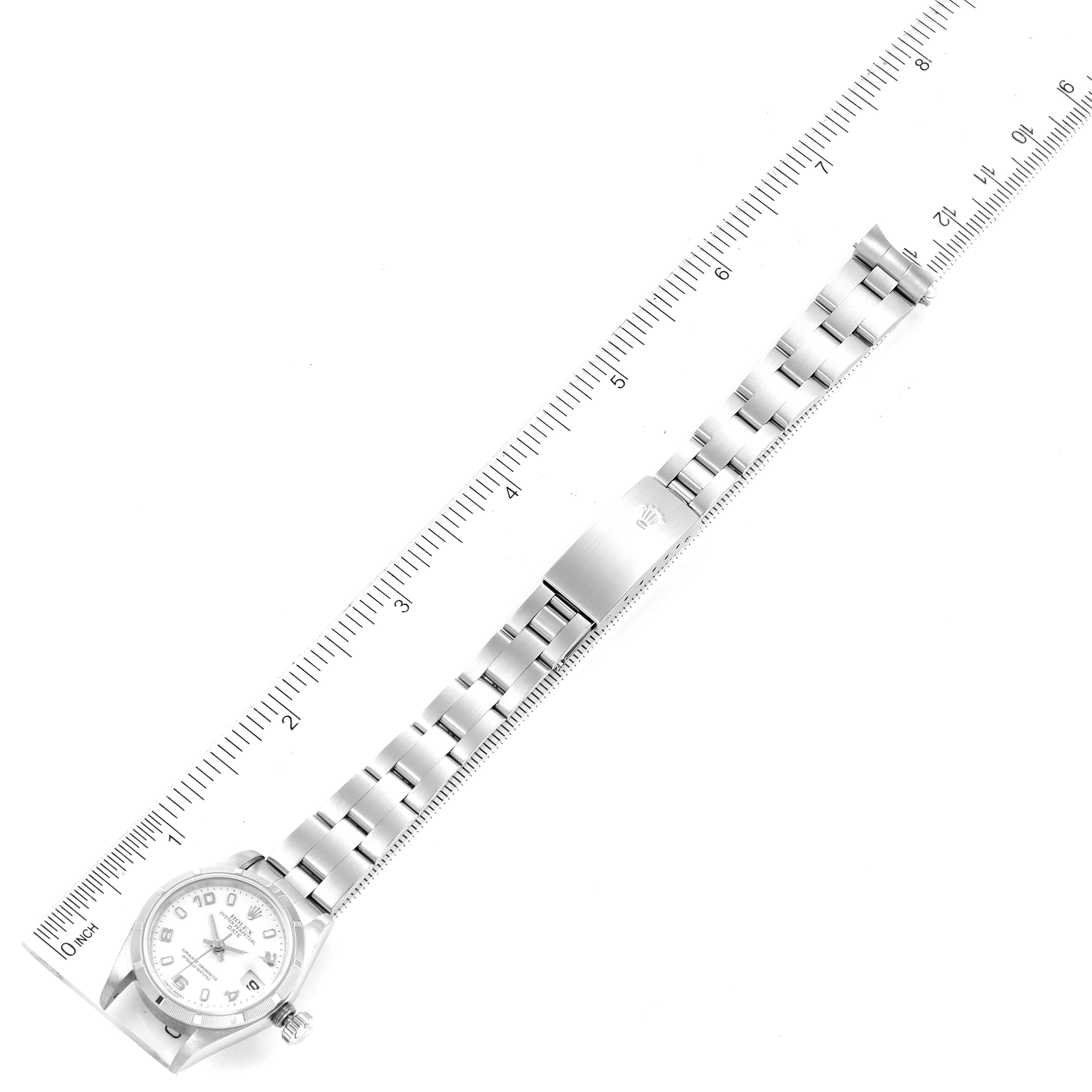 The Rolex Date 79190 Women's Stainless Steel White Dial 79190 Women's Stainless Steel White Dial model watch is shown from a top-down angle, displaying the entire bracelet and clasp next to a ruler.