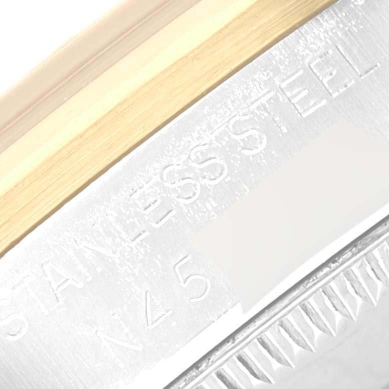 The image shows an angled close-up of a Rolex Mid-Size 68243 Women's Steel and Gold (two tone) Beige Dial 68243 Women's Steel and Gold (two tone) Beige Dial watch's stainless steel case and part of its engraved serial number.