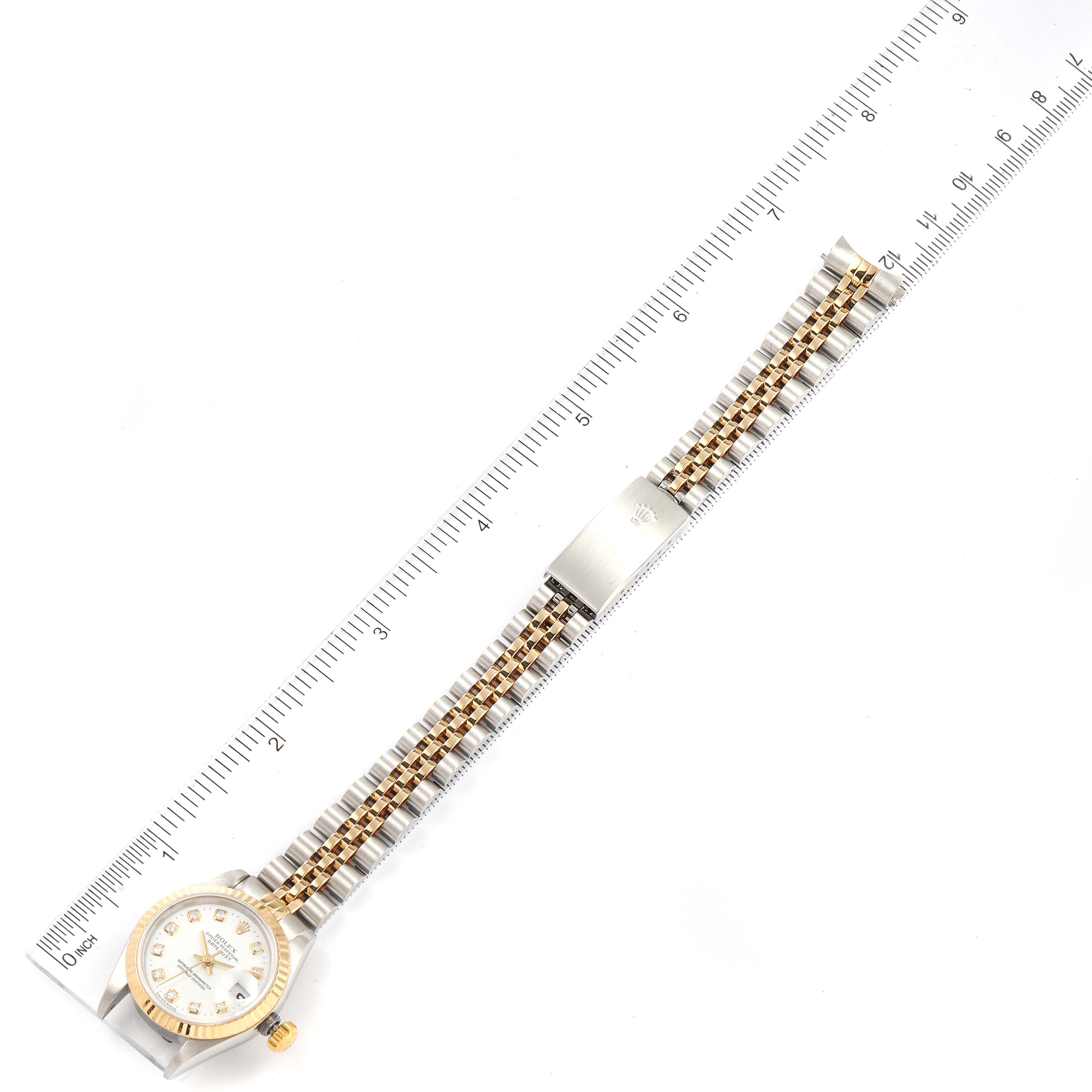 The image shows a Rolex Datejust 79173 Women's Steel and Gold (two tone) White Dial 79173 Women's Steel and Gold (two tone) White Dial watch laid flat next to a ruler, displaying the face, bracelet, and clasp.
