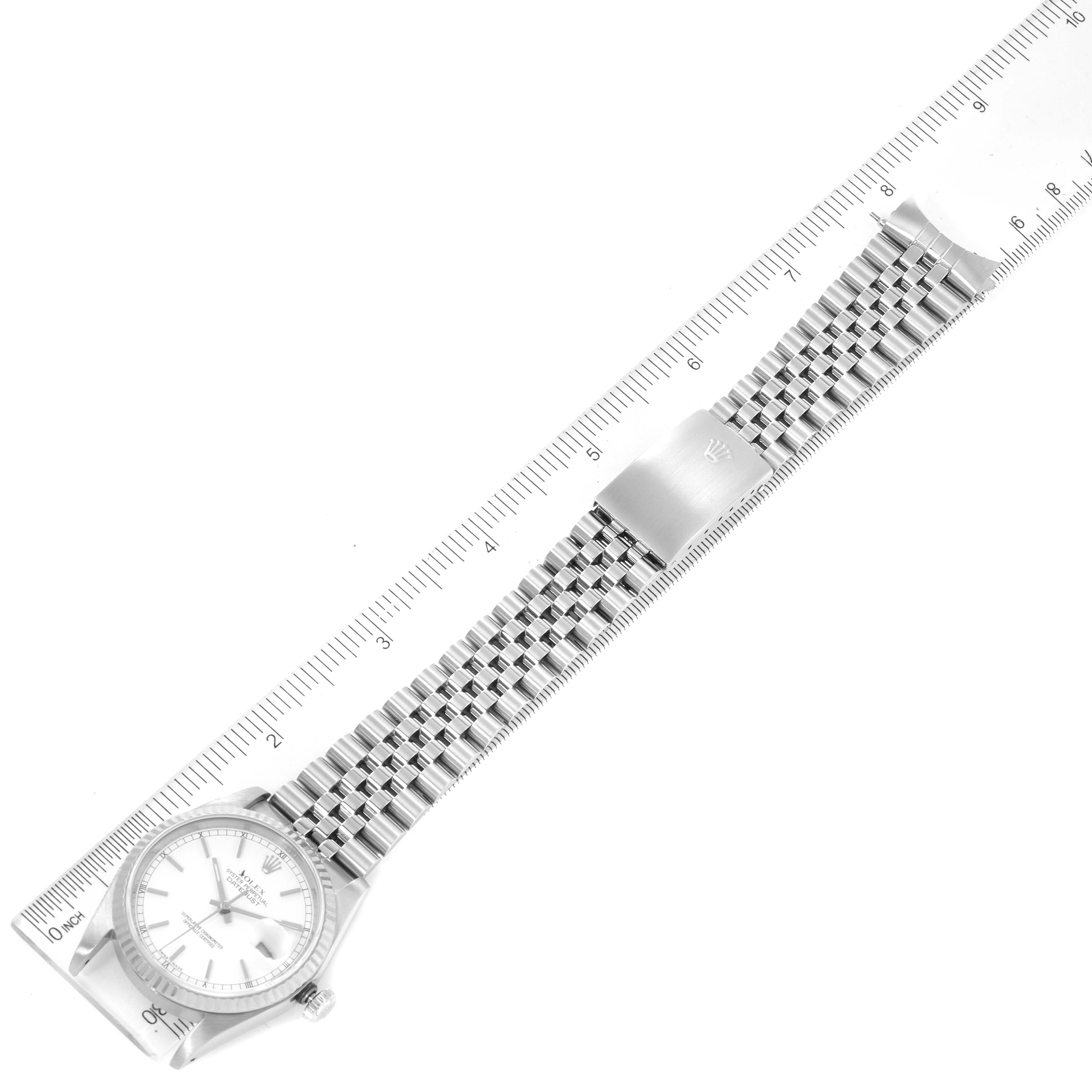 The image displays a top-down view of a Rolex Datejust 16234 Men's Stainless Steel White Dial 16234 Men's Stainless Steel White Dial watch with a Jubilee bracelet and a ruler alongside it.