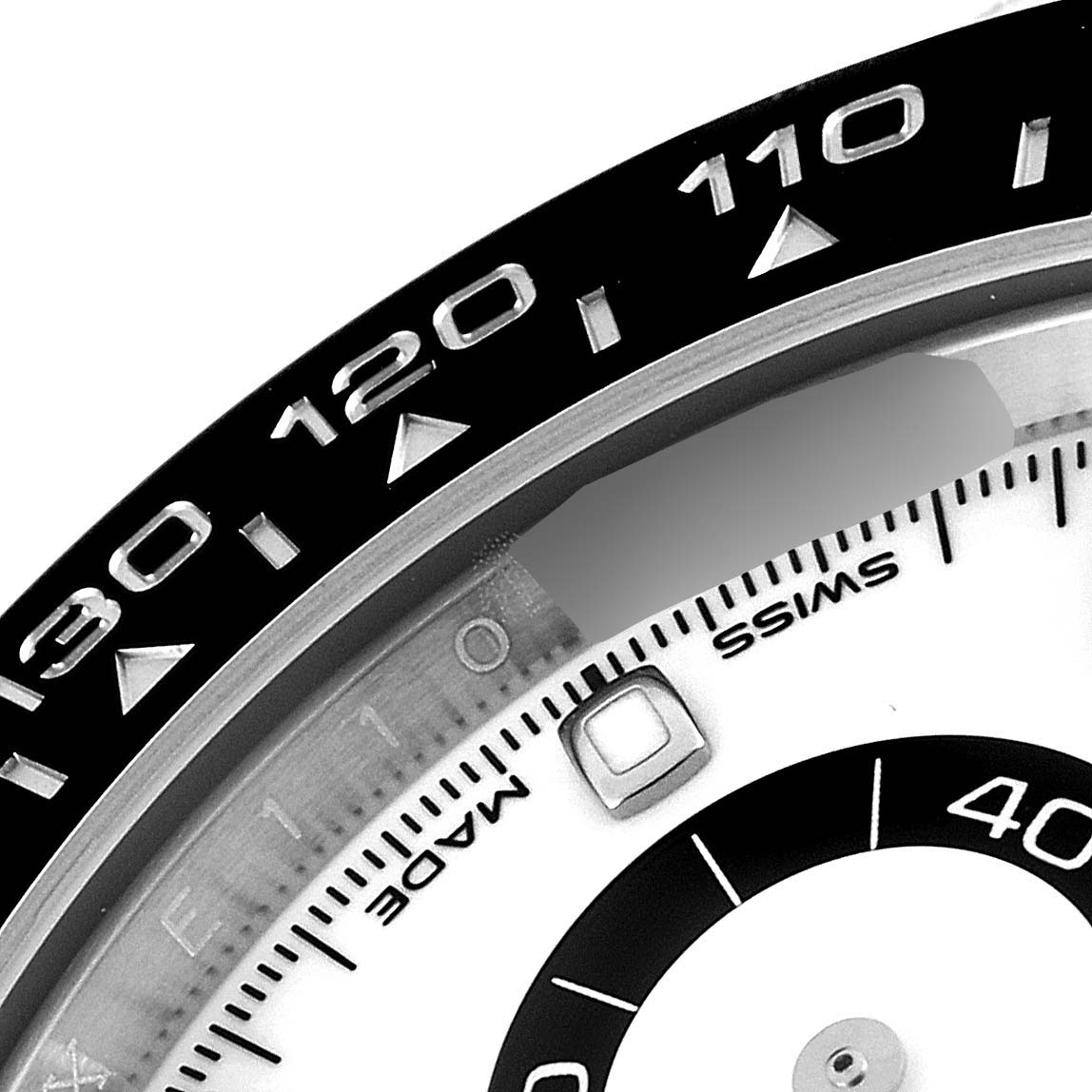 The image shows a close-up of the bezel and part of the dial of a Rolex Daytona 116500 Men's Stainless Steel White Dial 116500 Men's Stainless Steel White Dial watch.