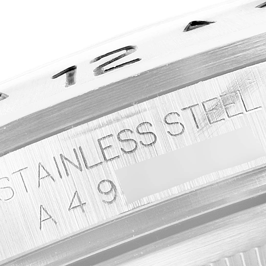 The image shows a close-up of the side of a Rolex Explorer 16570 Men
s Stainless Steel Black Dial 16570 Men
s Stainless Steel Black Dial watch, revealing "STAINLESS STEEL" engraving and partial numbers.