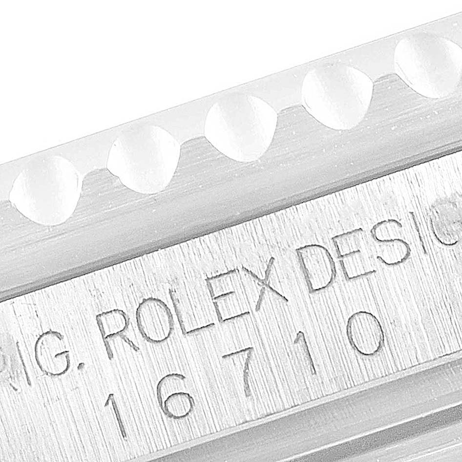 The image shows a close-up view of the side of a Rolex GMT-Master 16710 Men
s Stainless Steel Black Dial 16710 Men
s Stainless Steel Black Dial watch, highlighting its model number 16710 and Rolex Design engraving.