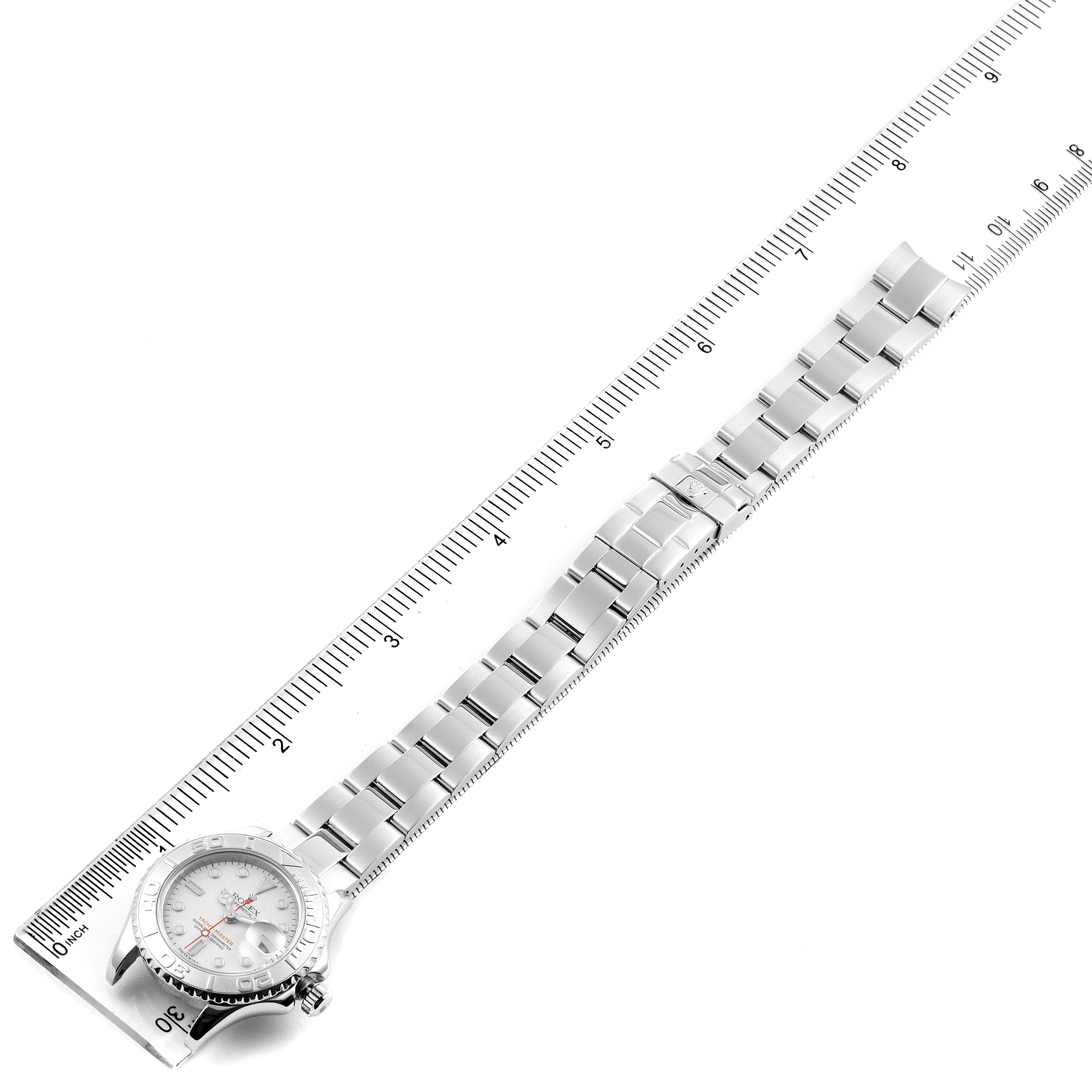 The Rolex Yacht-Master 169622 Women's Stainless Steel Silver Dial 169622 Women's Stainless Steel Silver Dial watch is shown from a top-down angle, featuring its entire metal strap and case near a ruler for size reference.