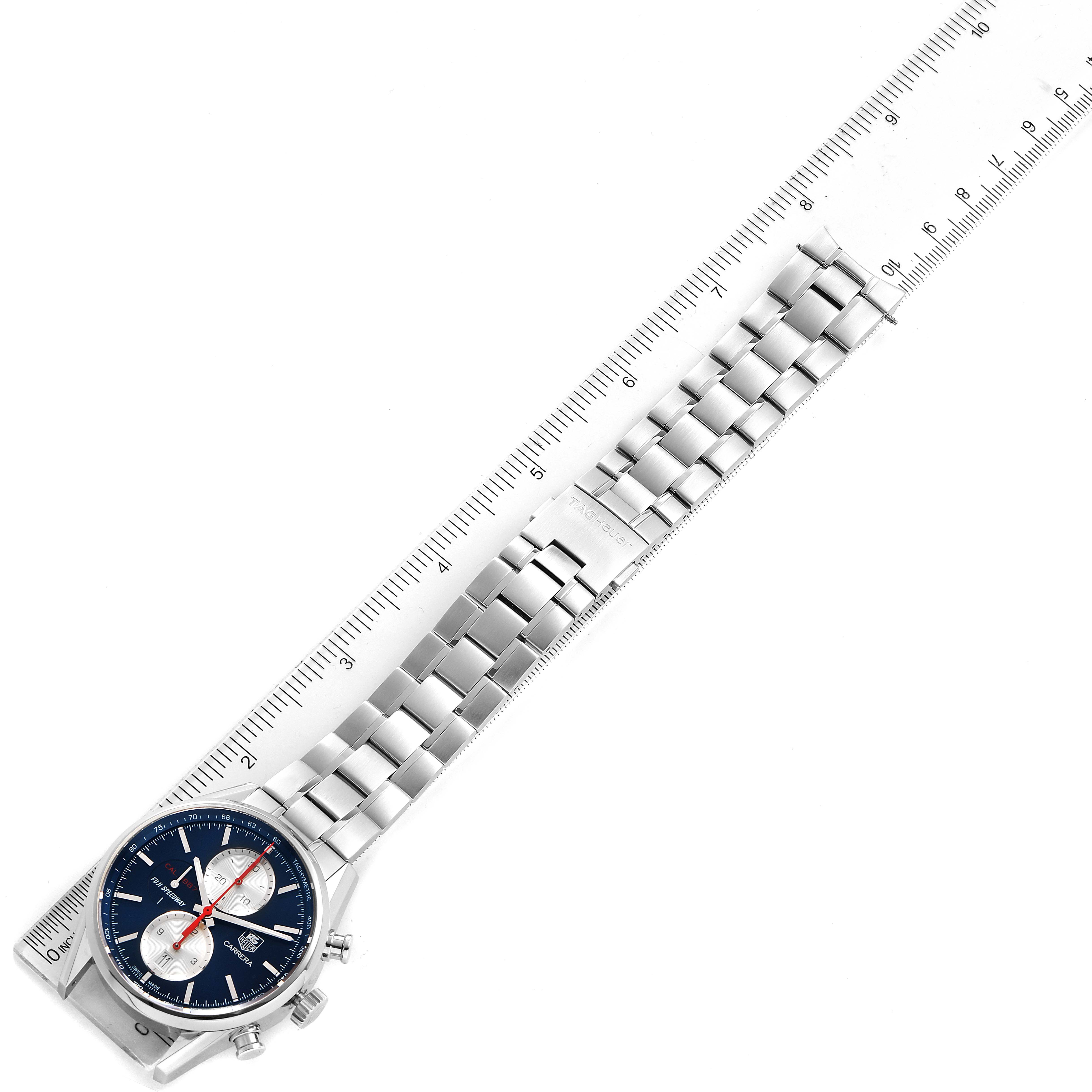 The image shows a Tag Heuer Carrera watch with a metal strap aligned beside a ruler.