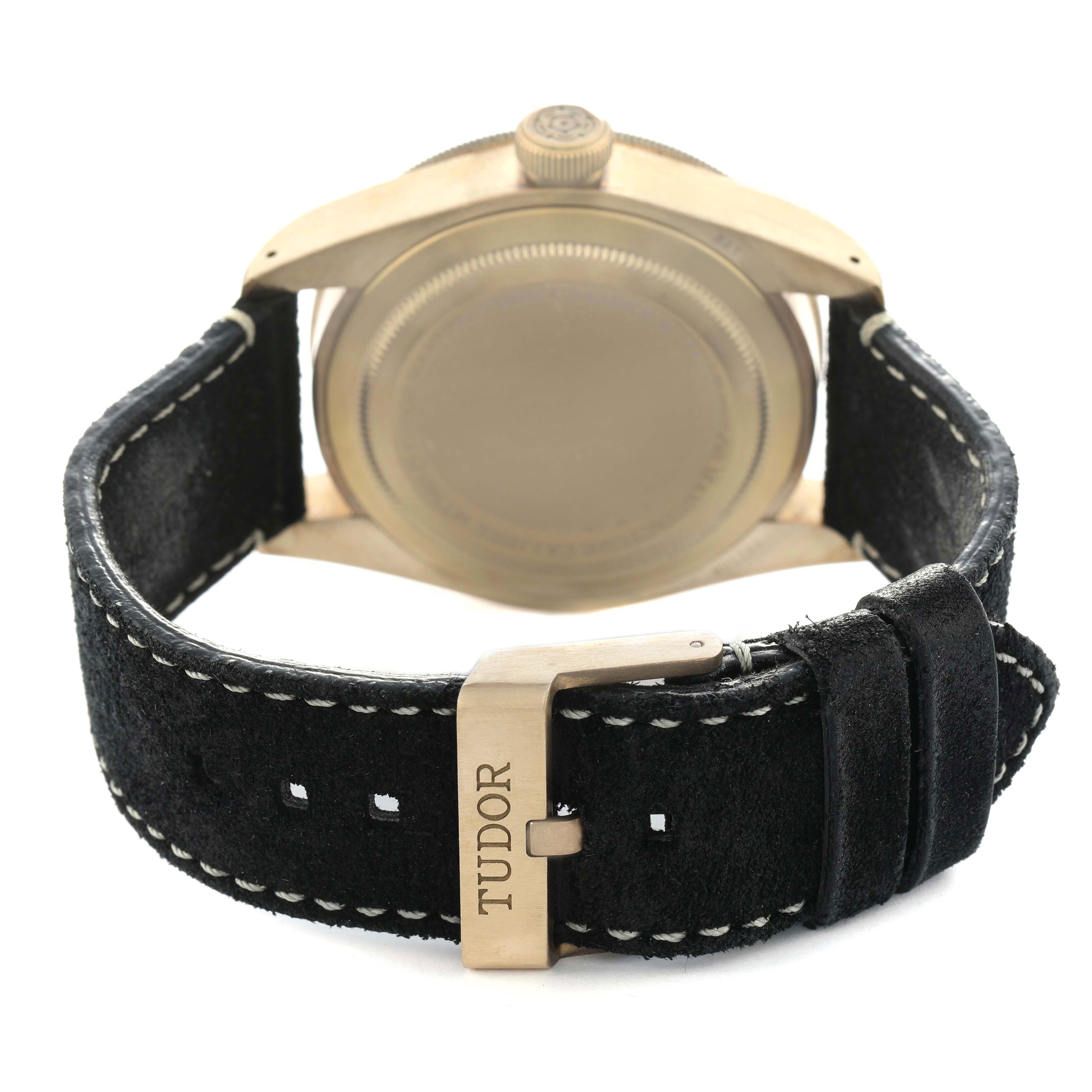 The Tudor Heritage Black Bay 79250 Men's Bronze Black Dial watch is shown from the back, highlighting the case back, crown, and leather strap with a buckle.