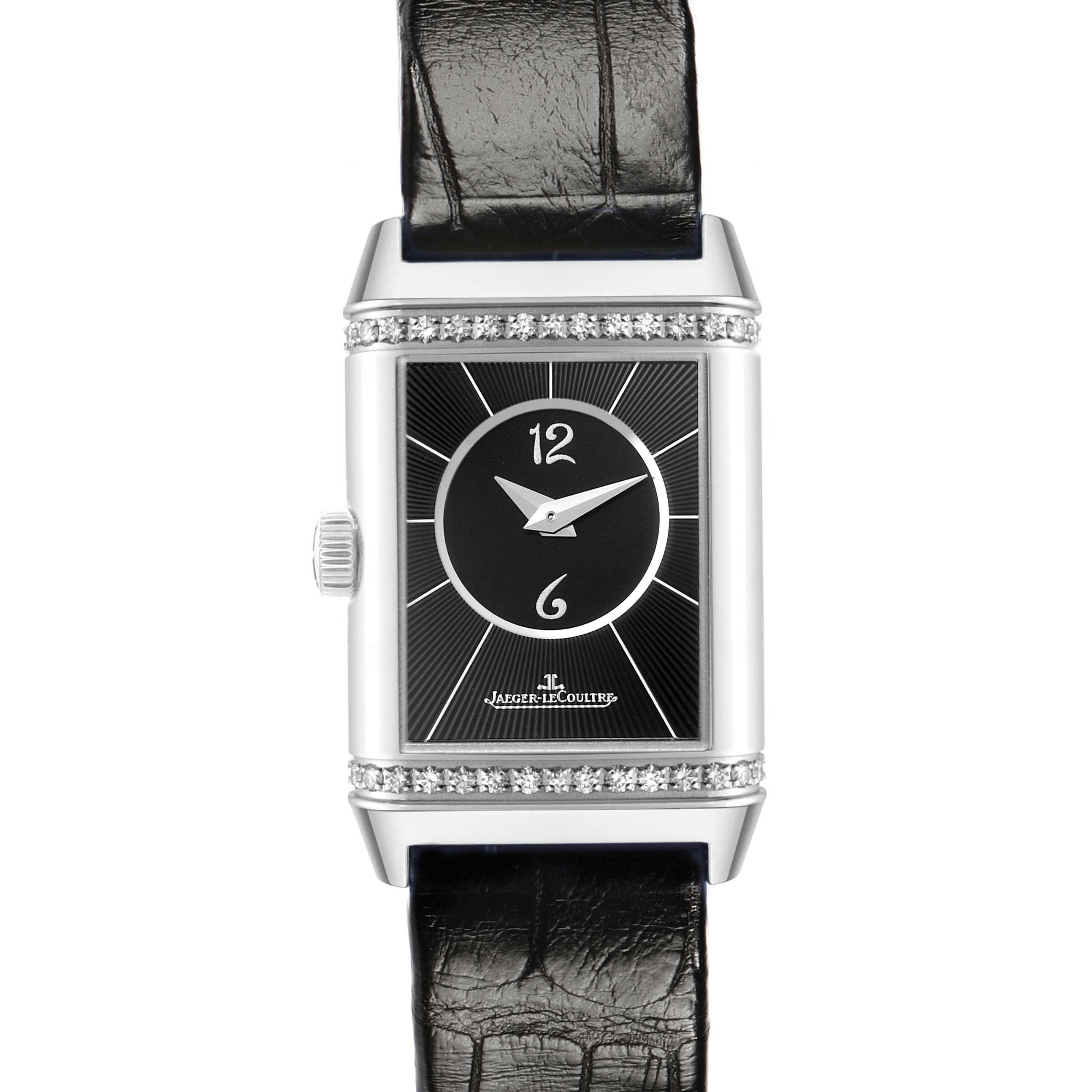 The Jaeger-LeCoultre Reverso watch is shown from the front, displaying its rectangular face, black dial, straps, and diamond accents.