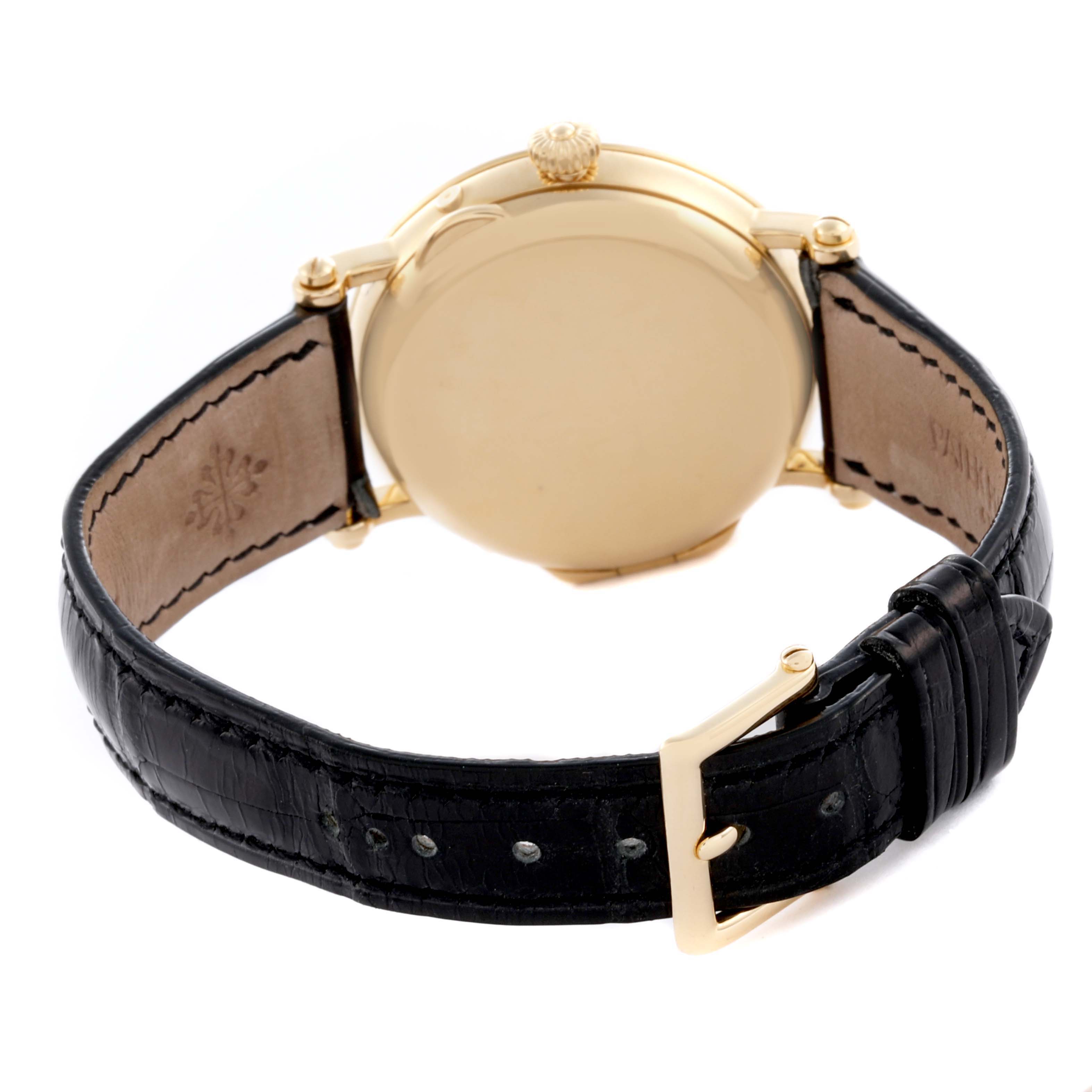 The image shows the back and side crown of a Patek Philippe Complications 5054 Men's Yellow Gold White Dial 5054 Men's Yellow Gold White Dial watch with a black leather strap.