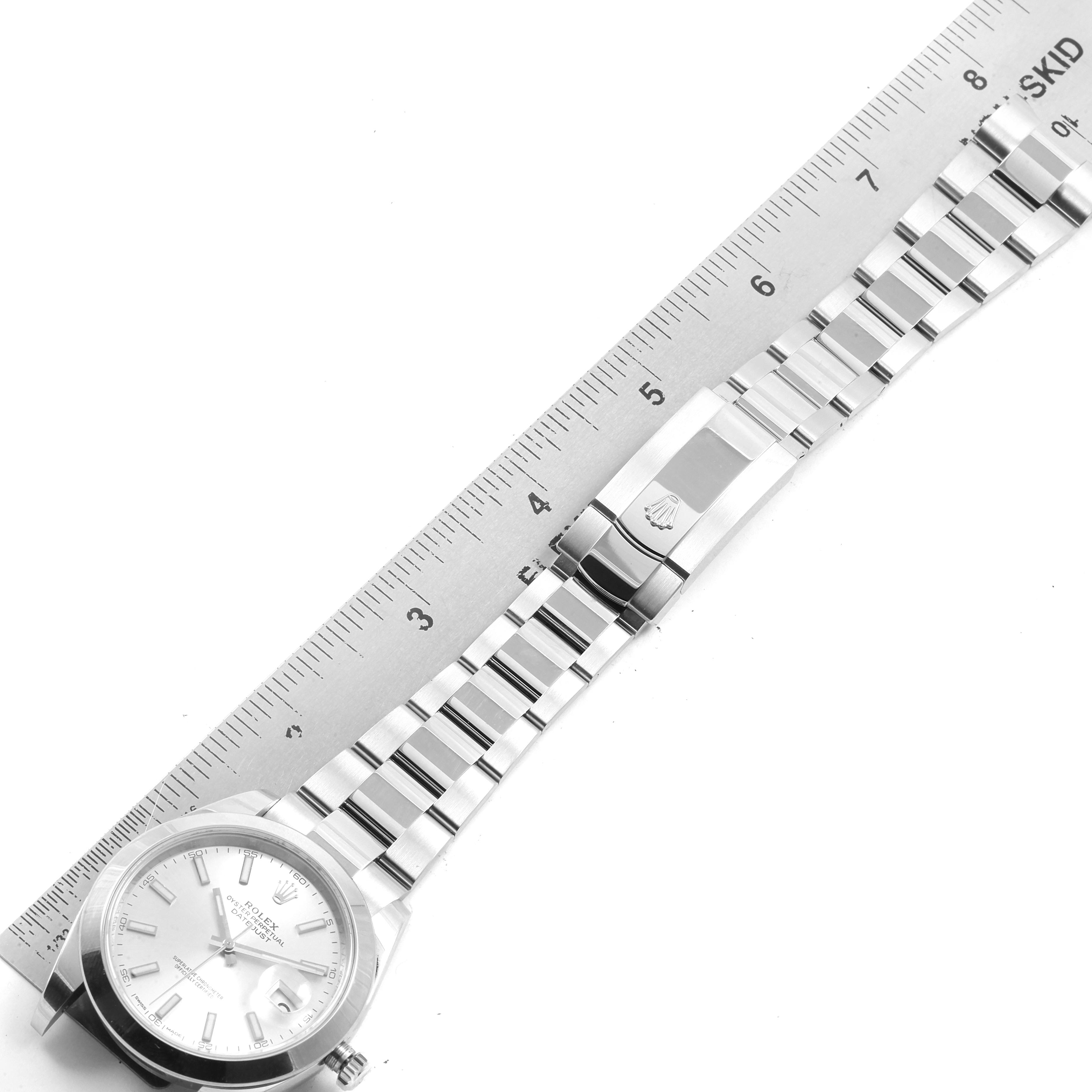 The image shows the Rolex Datejust 41 126300 Men
s Stainless Steel Silver Dial 126300 Men
s Stainless Steel Silver Dial model watch lying flat with a ruler parallel to its bracelet.