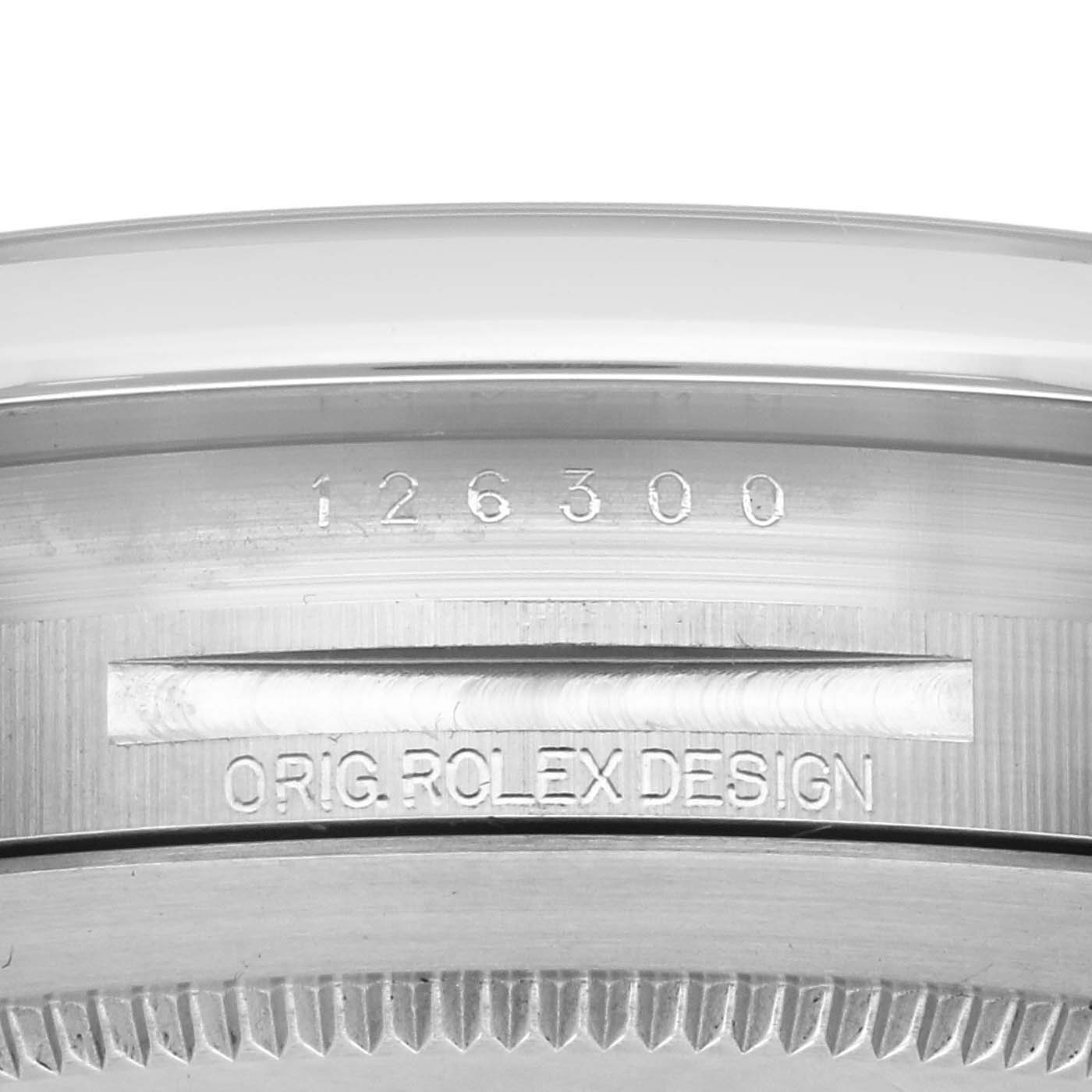 The image shows the side of the Rolex Datejust 126300 Men
s Stainless Steel Silver Dial 126300 Men
s Stainless Steel Silver Dial with the model number and "ORIG. ROLEX DESIGN" engraved on the case.
