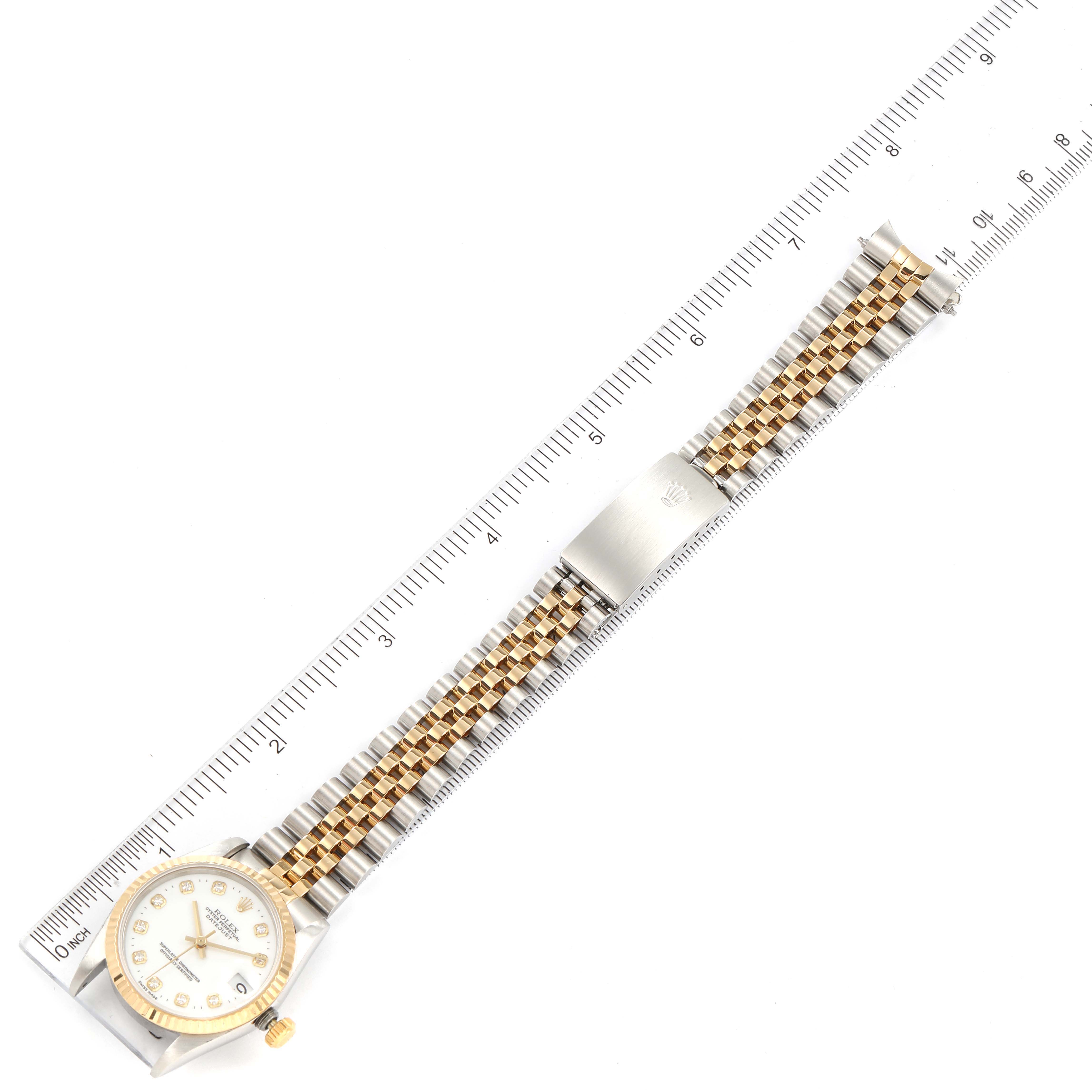 The image shows a Mid-Size Rolex watch laid flat with a ruler, displaying the entire watch including the face, bracelet, and clasp.