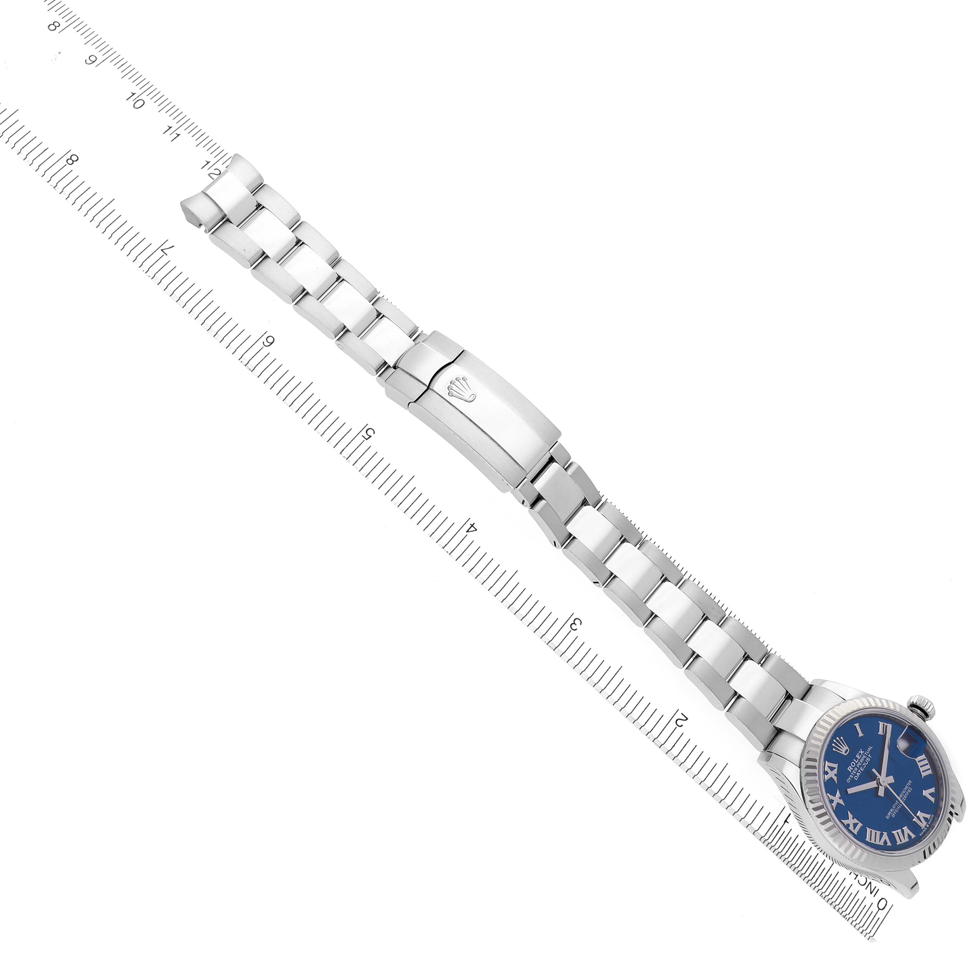 The image shows a top-down view of a Rolex Mid-Size 278274 Women's Stainless Steel Blue Dial 278274 Women's Stainless Steel Blue Dial watch with a blue dial and full bracelet, alongside a ruler for scale.