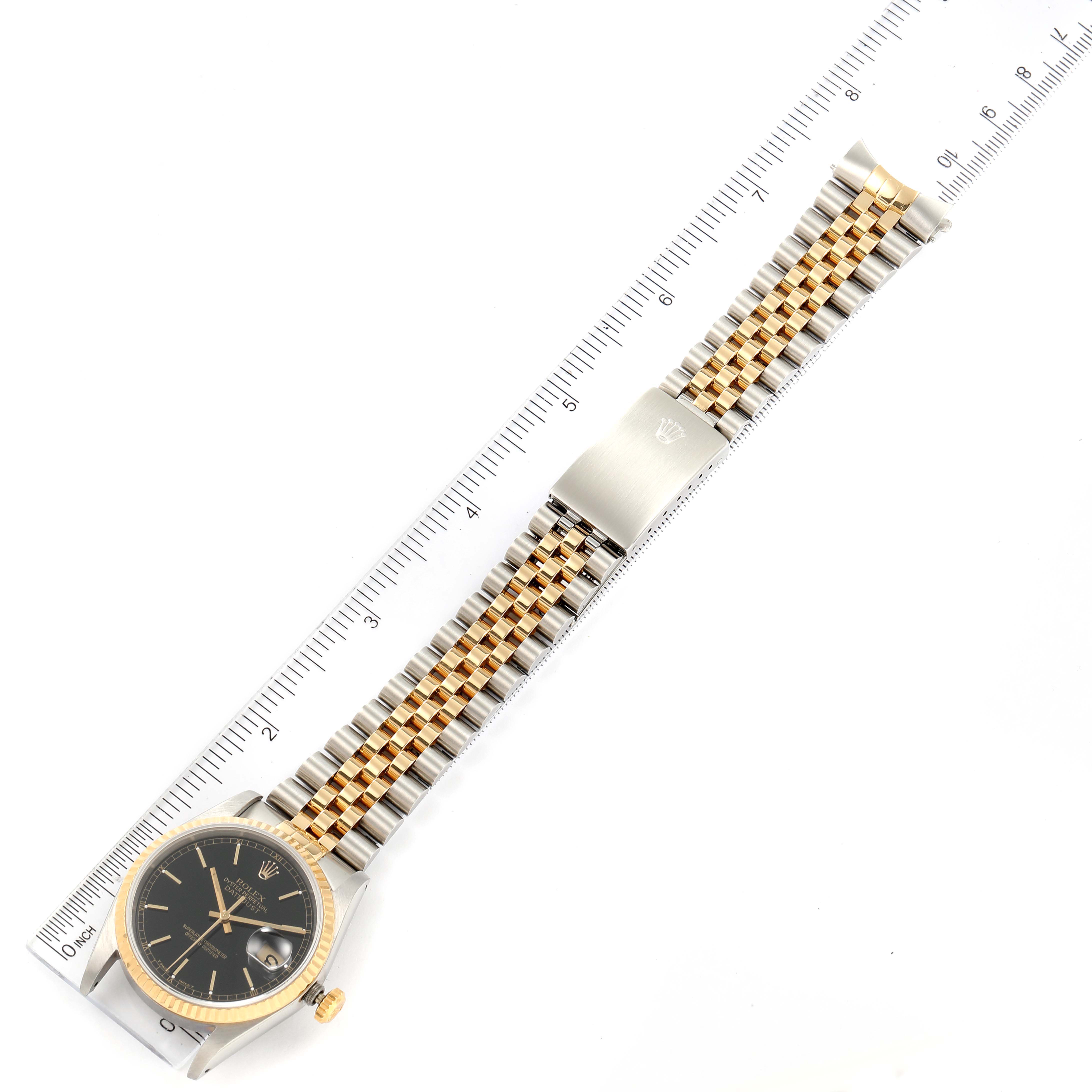 The image shows a Rolex Datejust 16233 Men's Steel and Gold (two tone) Black Dial 16233 Men's Steel and Gold (two tone) Black Dial watch laid flat with its bracelet extending alongside a ruler for scale.