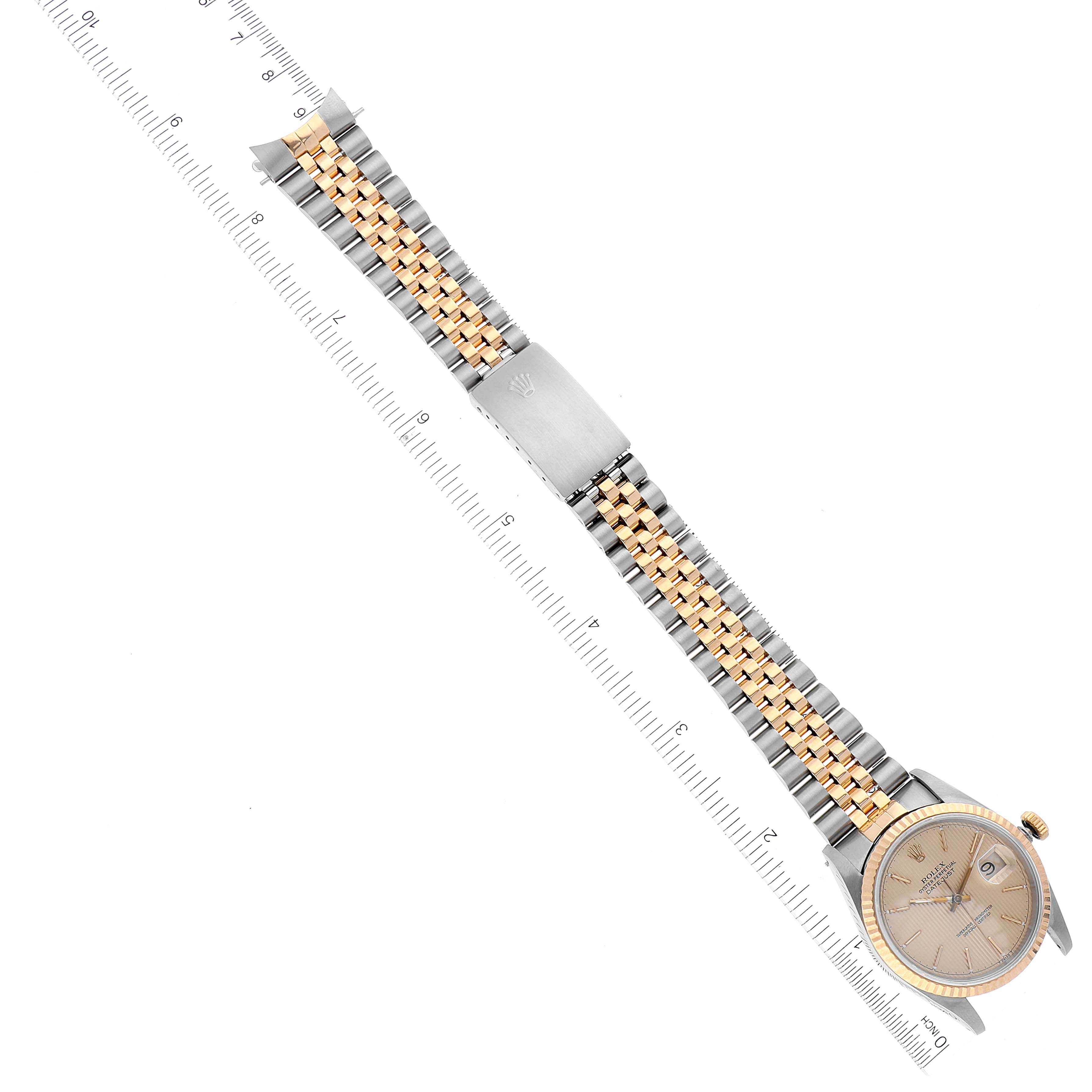 The image shows a Rolex Datejust 16233 Men's Steel and Gold (two tone) Champagne Dial 16233 Men's Steel and Gold (two tone) Champagne Dial watch from an overhead angle, highlighting the dial, bracelet, and clasp against a ruler backdrop.