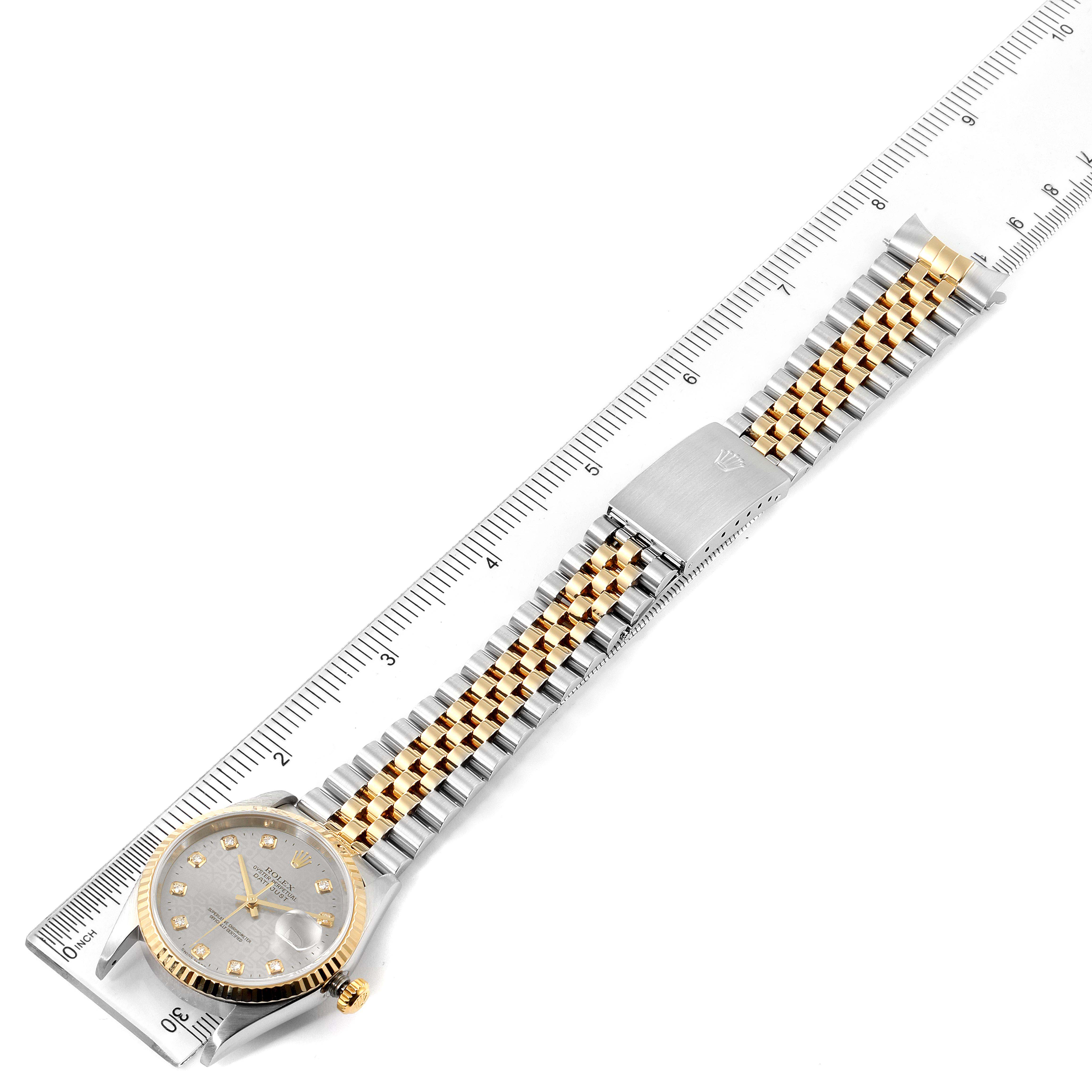 The Rolex Datejust 16233 Men's Steel and Gold (two tone) Silver Dial 16233 Men's Steel and Gold (two tone) Silver Dial watch is shown from the top, displaying its face, bracelet, and clasp against a ruler for scale.