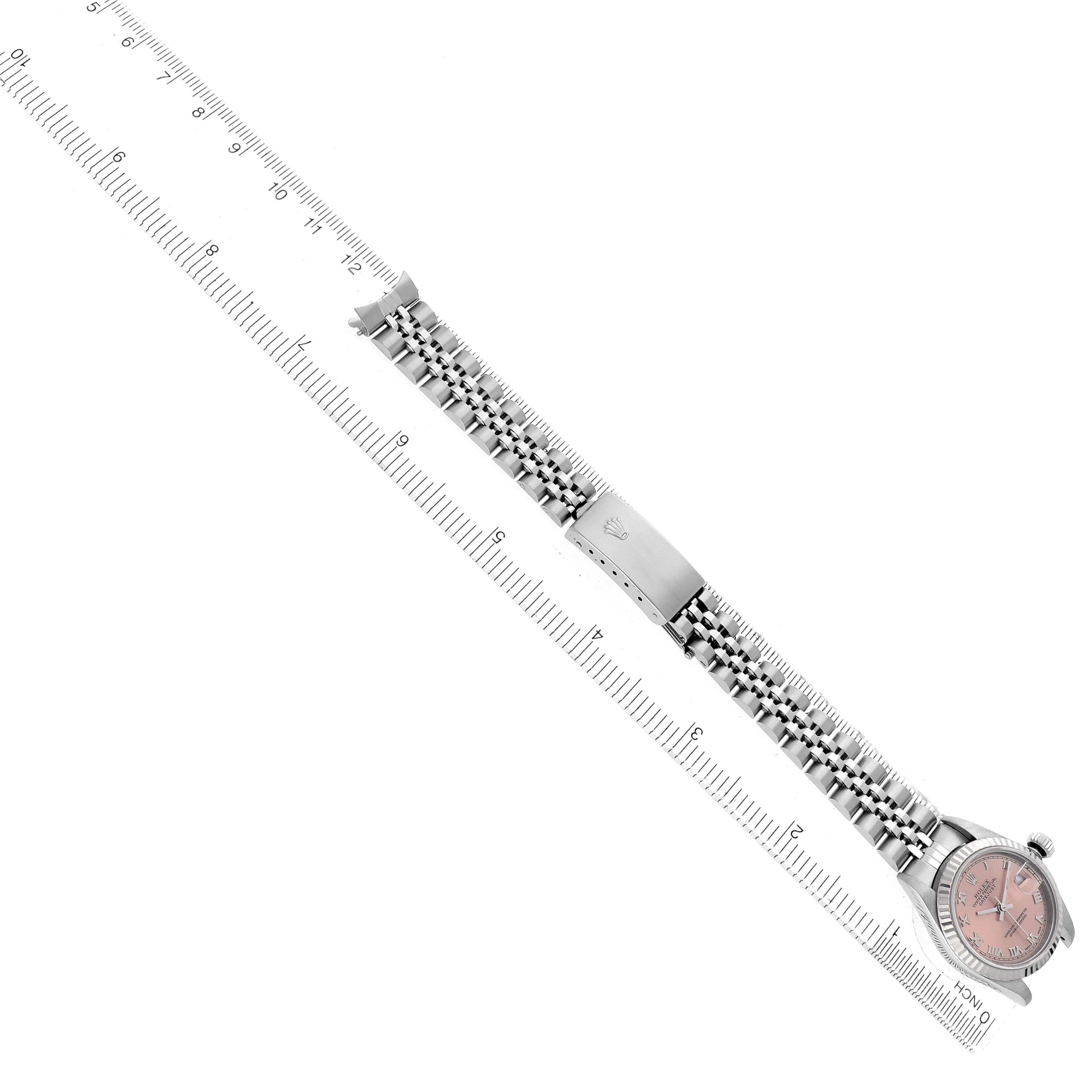 The Rolex Datejust 79174 Women's Stainless Steel Pink Dial is shown from an overhead angle, highlighting its face, bracelet, and clasp, alongside a ruler for scale.
