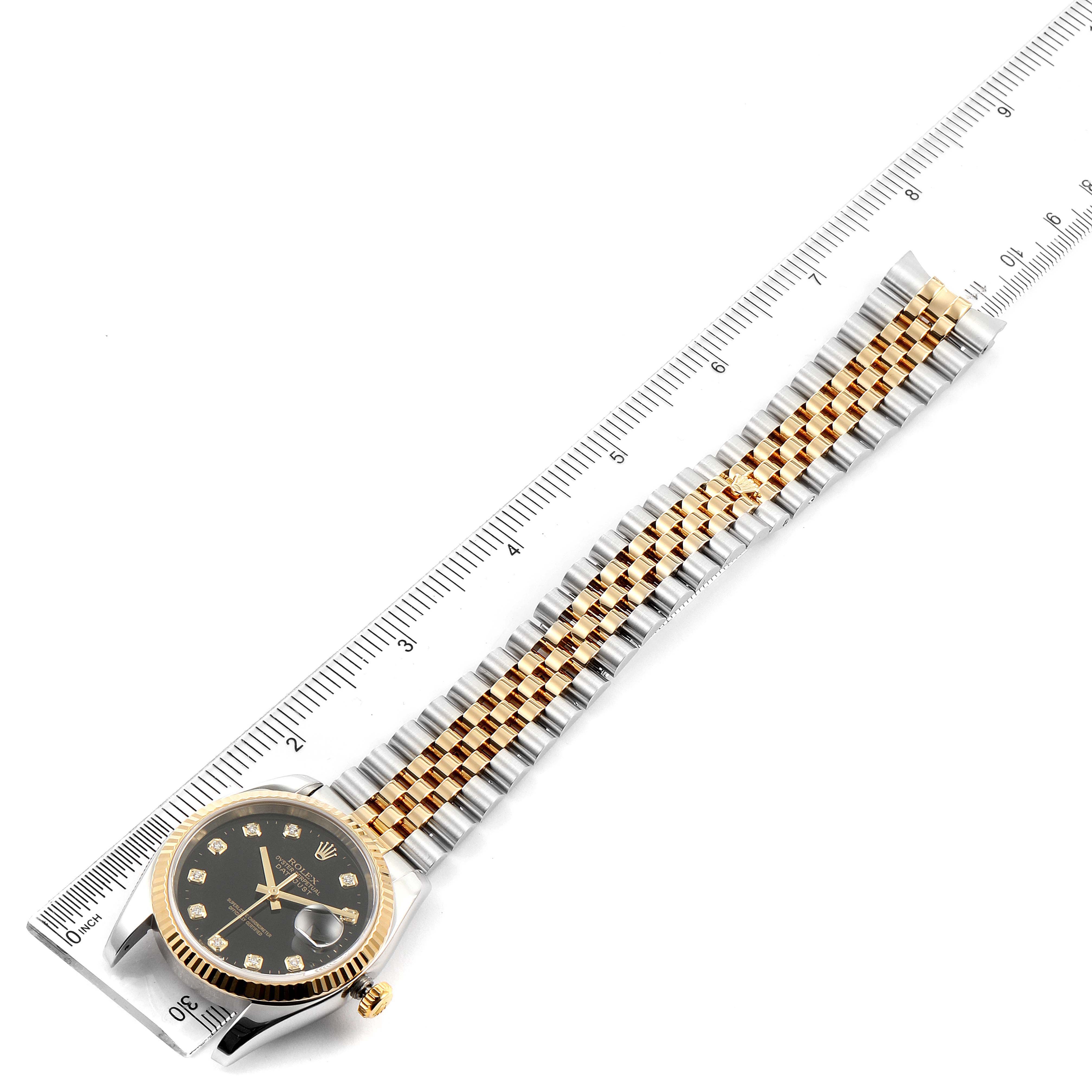 The Rolex Datejust 116233 Men's Steel and Gold (two tone) Black Dial 116233 Men's Steel and Gold (two tone) Black Dial watch is shown from an overhead angle, displaying the face, bezel, and bracelet against a ruler for scale.