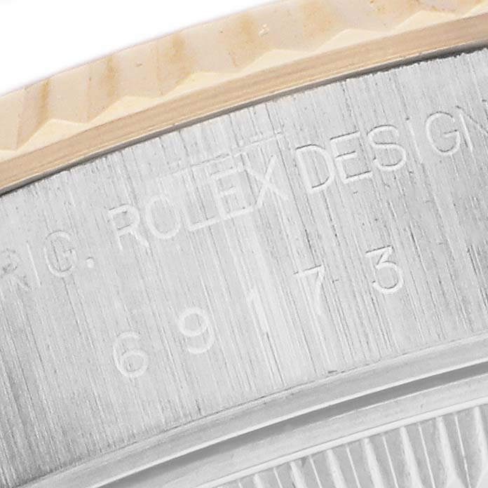 The image shows a close-up of a Rolex Datejust 69173 Women's Steel and Gold (two tone) Champagne Dial model, highlighting the engraved edge and part of the fluted bezel.