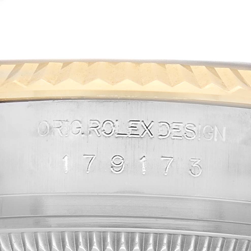 The image shows a close-up of the case edge and engraved details on a Rolex Datejust 179173 Women's Steel and Gold (two tone) Black Dial model.