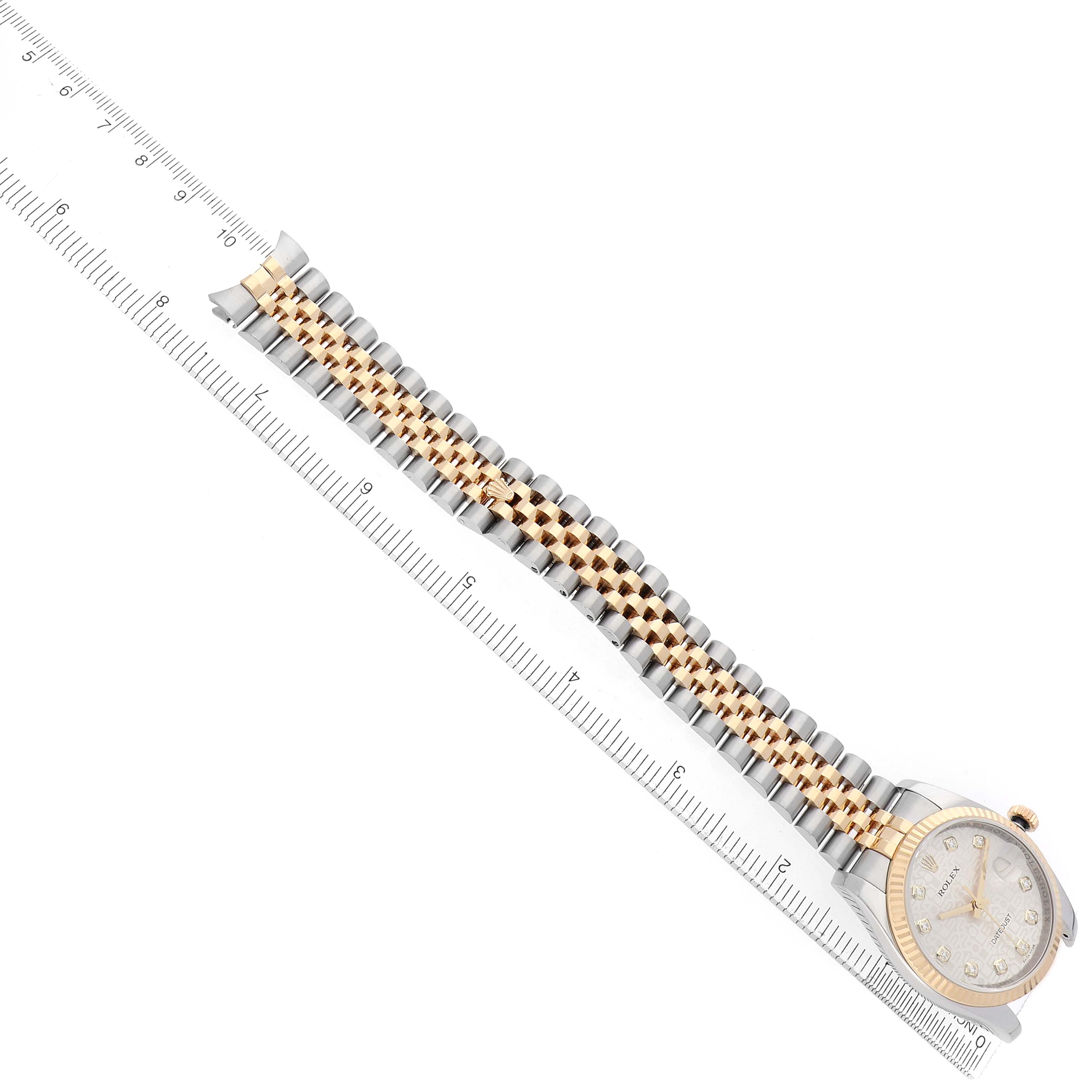 The Rolex Datejust 116233 Men's Steel and Gold (two tone) Silver Dial is shown diagonally from a top view, displaying the dial, bezel, and full bracelet with a ruler for scale.