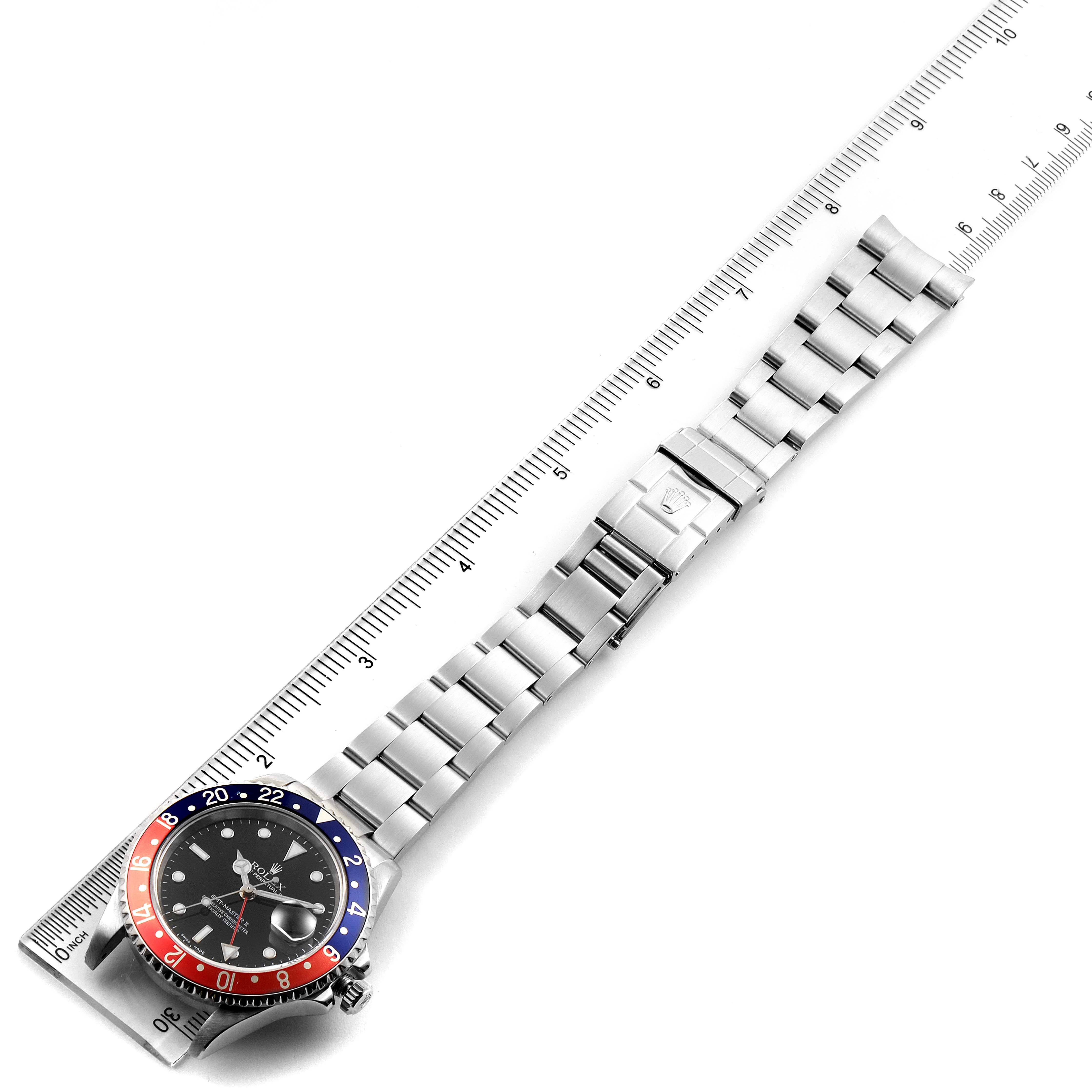 The Rolex GMT-Master 16710 Men
s Stainless Steel Black Dial 16710 Men
s Stainless Steel Black Dial watch is shown from a top-down angle, displaying the bezel, dial, and metal bracelet positioned alongside a ruler.