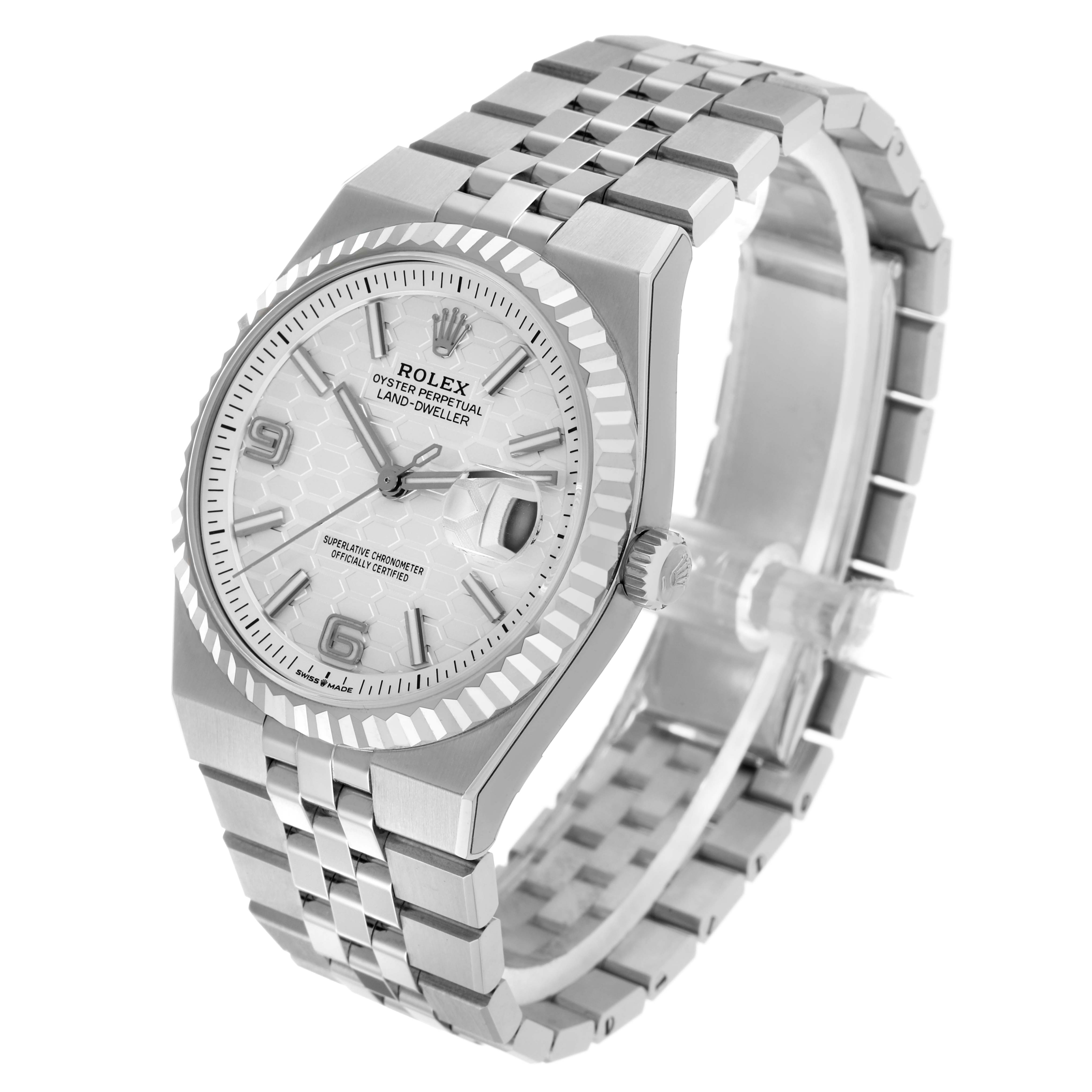 The Rolex Land-Dweller watch is shown at an angle highlighting the face, bezel, crown, and bracelet.