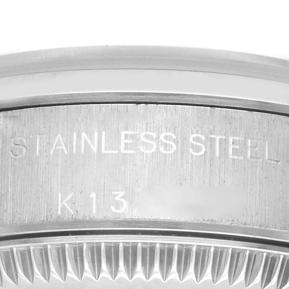 This image shows a close-up of the edge and side of a Rolex Oyster Perpetual 76080 Women's Stainless Steel Pink Dial 76080 Women's Stainless Steel Pink Dial, highlighting the "STAINLESS STEEL" engraving.
