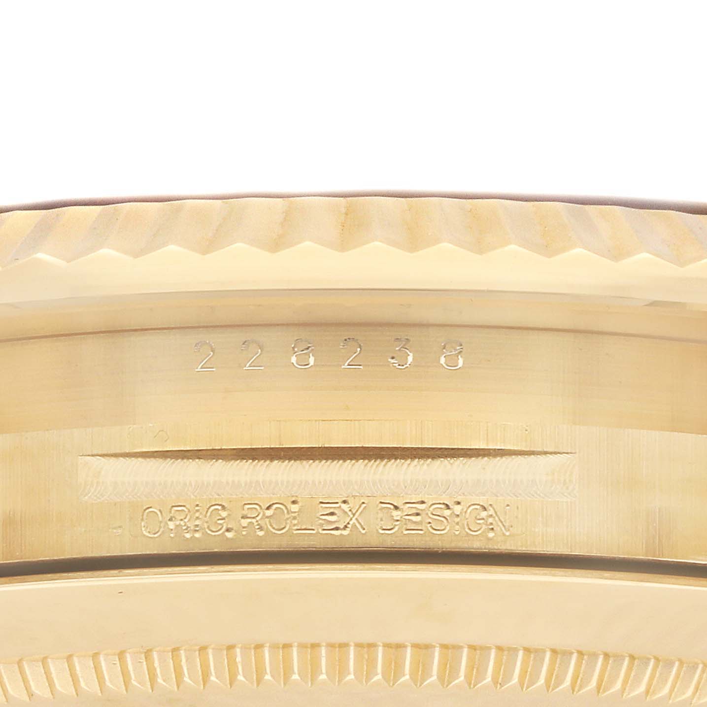The image shows an angled close-up of the case edge of a Rolex President 228238 Men's Yellow Gold Black Dial model, highlighting the serial number and "ORIG. ROLEX DESIGN" engraving.
