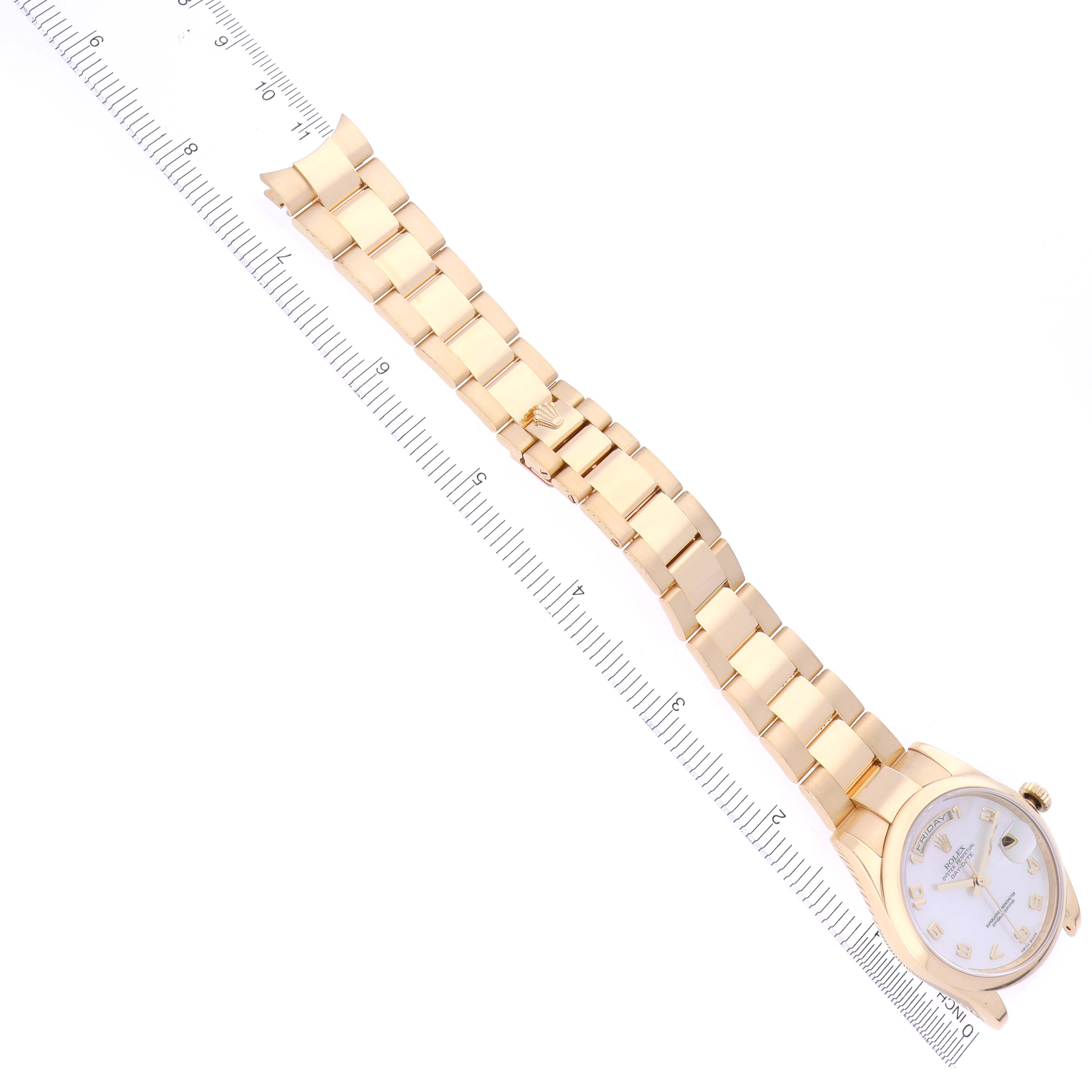 The Rolex President 118208 Men
s Yellow Gold Mother of Pearl Dial 118208 Men
s Yellow Gold Mother of Pearl Dial model watch is shown from a top-down angle, displaying the gold bracelet and face alongside a ruler for scale.