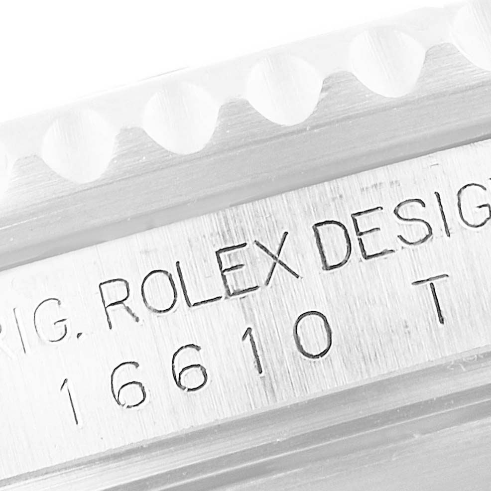 The image shows a close-up of the Rolex Submariner 16610 Men
s Stainless Steel Black Dial 16610 Men
s Stainless Steel Black Dial
s engraved serial number and part of the watch bezel.