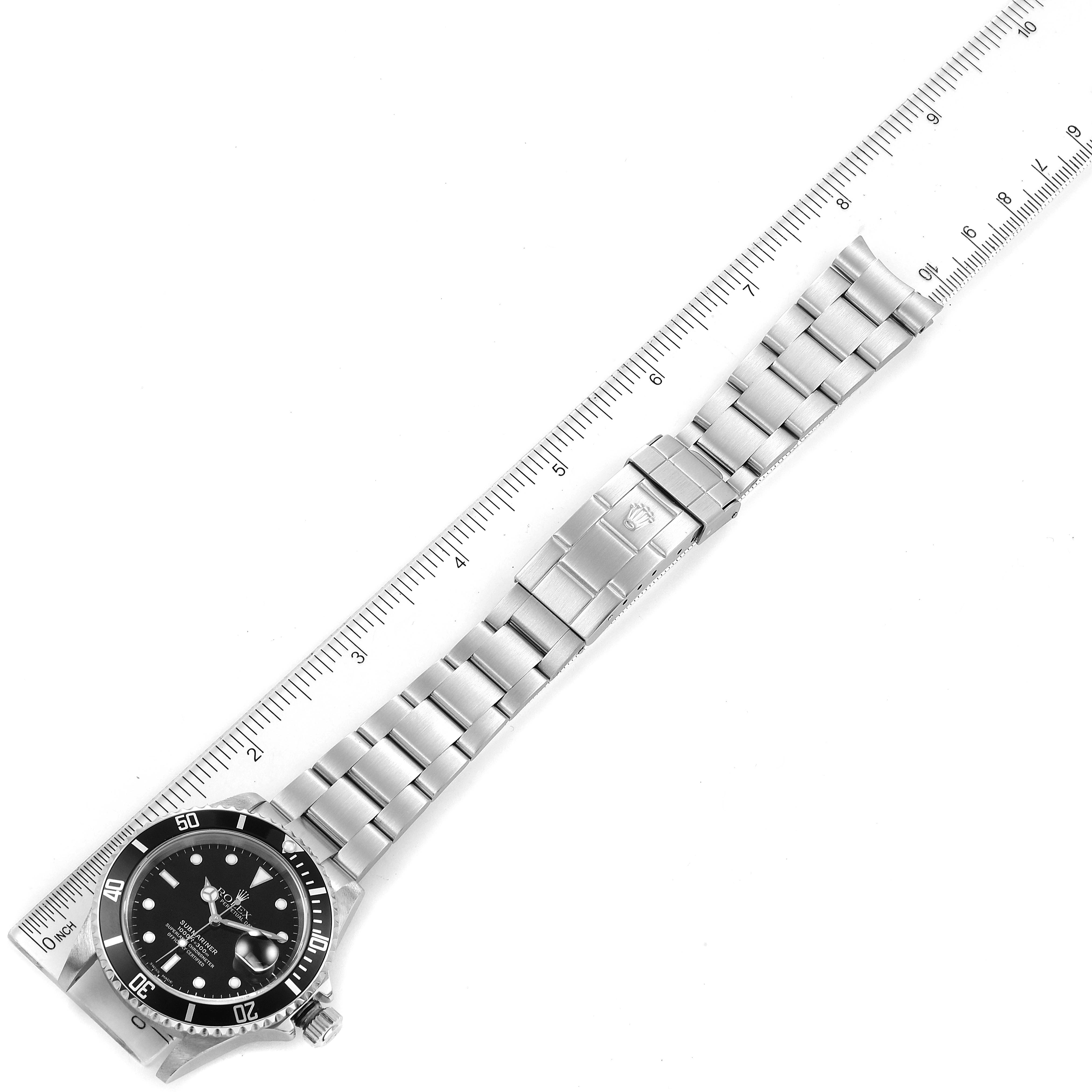 This image shows a full view of a Rolex Submariner 16610 Men
s Stainless Steel Black Dial 16610 Men
s Stainless Steel Black Dial watch, including the case, dial, and bracelet, next to a ruler for scale.