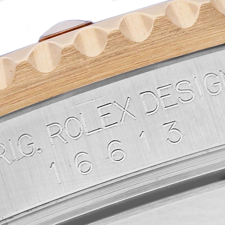 The image shows the side of a Rolex Submariner 16613 Men's Steel and Gold (two tone) Blue Dial 16613 Men's Steel and Gold (two tone) Blue Dial's case, featuring the engraved model number and part of the bezel.
